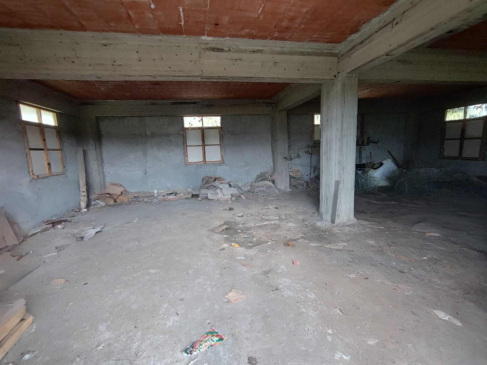 Solaio in fase di ristrutturazione con muratura in cemento, finestrini naturali, e pavimentazione grezza, pronto per lavori di finitura e rifacimento in un progetto di ristrutturazione immobiliare.