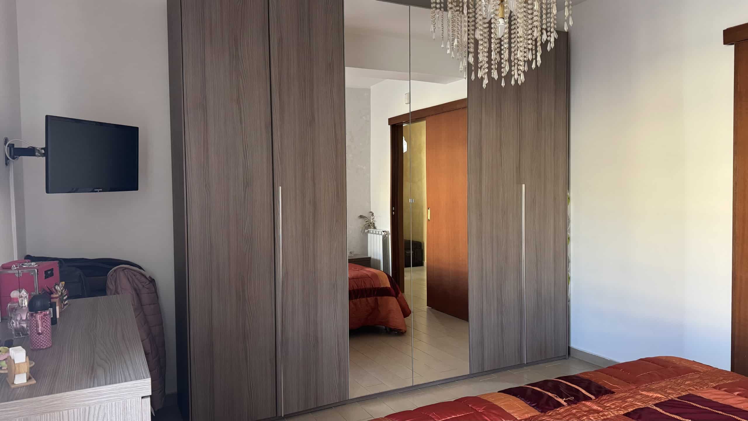 Armadio a muro moderno con specchi nel soggiorno, arredamento elegante e funzionale, ideale per ottimizzare gli spazi in casa. Perfetto per la soluzione di storage in ambienti residenziali.