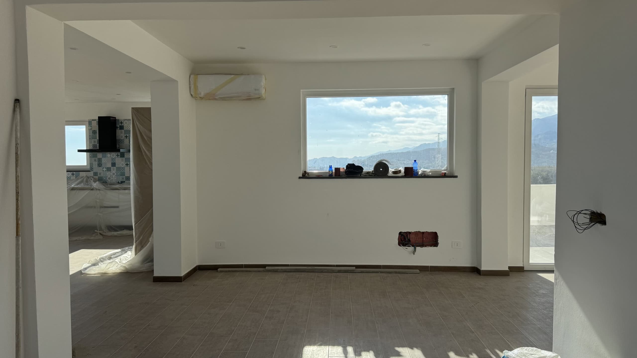 Nuova costruzione appartamento non arredato interni in fase di finitura con vista panoramica sulle montagne, ampi spazi luminosi, lavori di ristrutturazione in corso, stile moderno.