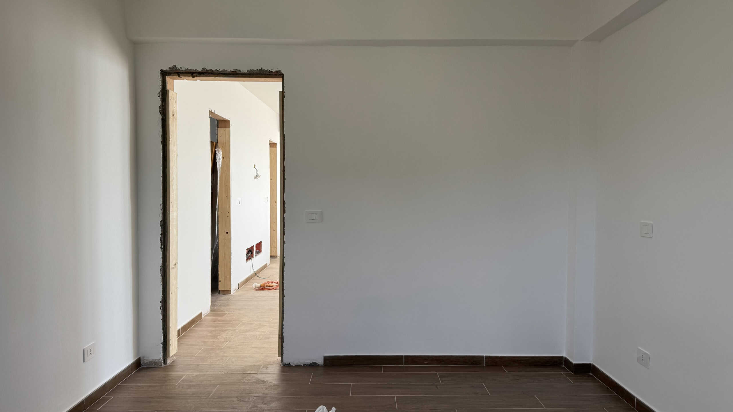 Posa di una stanza in fase di ristrutturazione, pareti bianche e pavimento in legno, pronti lavori di finitura e miglioramento immobiliare.