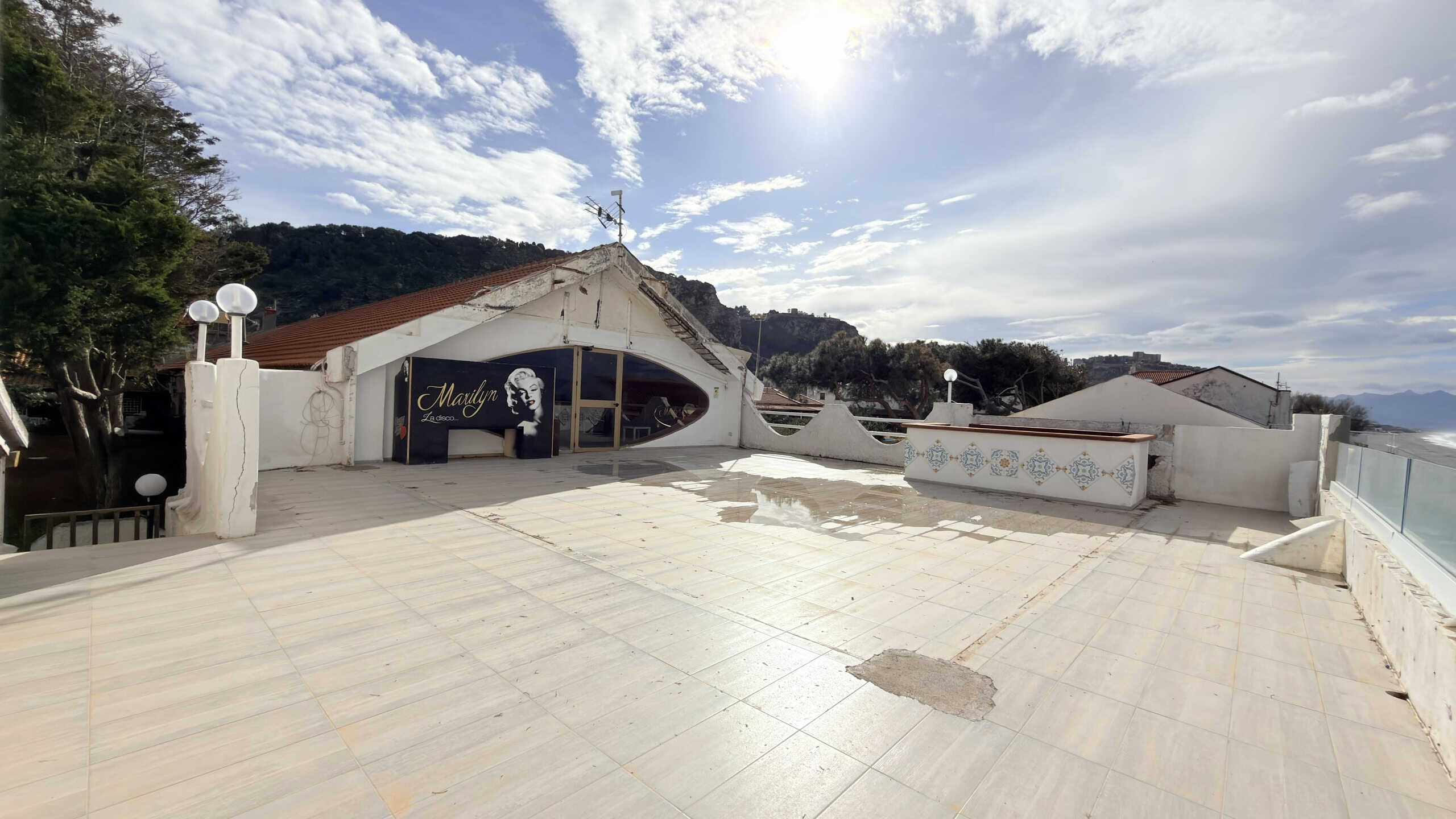 Terrazza panoramica con vista mare e decorazioni artistiche, ideale per eventi e relax, arredamento elegante e vista mozzafiato sulle colline e il mare.
