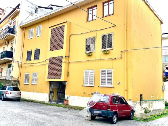 Affitto appartamento a Napoli con facciata gialla e finestre con persiane bianche, in quartiere residenziale, ideale per investimenti immobiliari e soluzioni abitative comode nel centro cittadino.