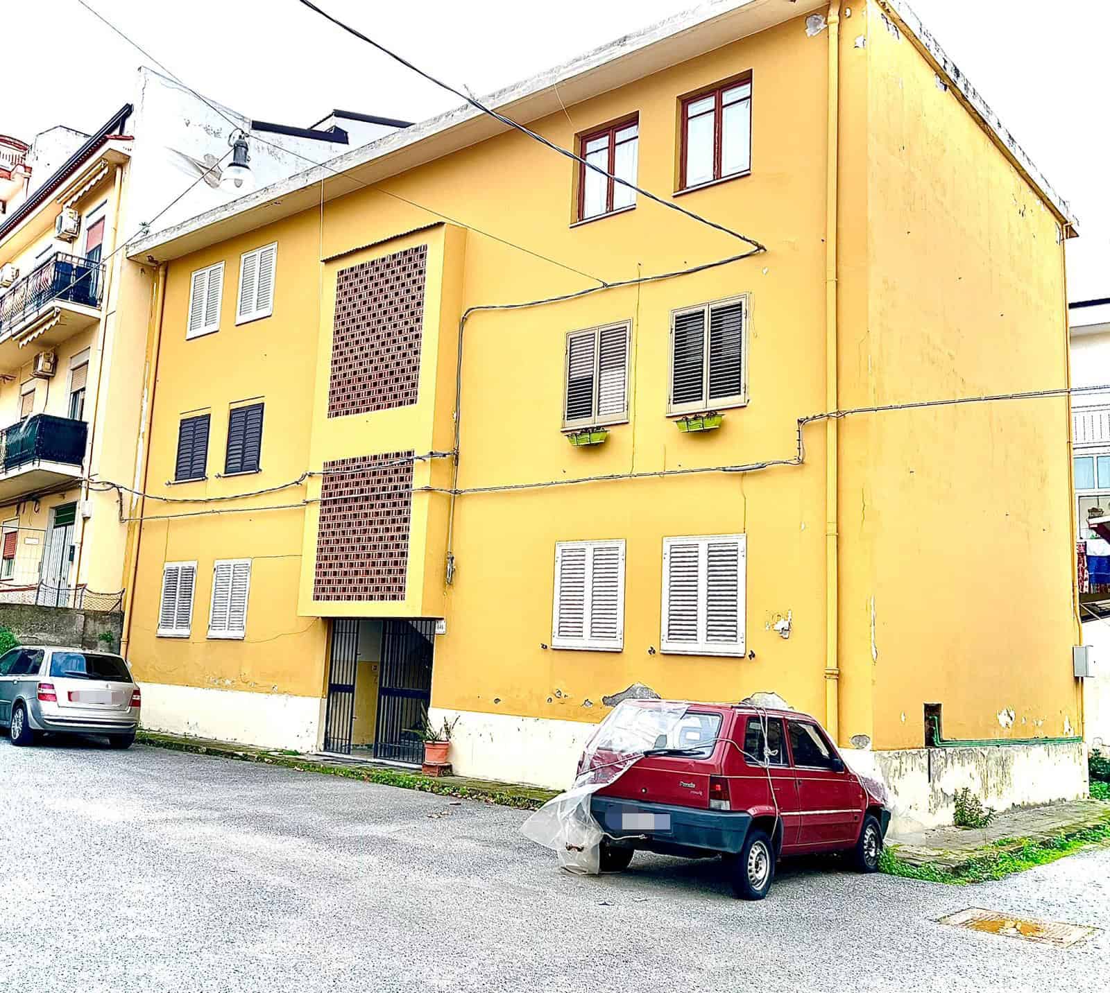 1 Affitto appartamento a Napoli con facciata gialla e finestre con persiane bianche, in quartiere residenziale, ideale per investimenti immobiliari e soluzioni abitative comode nel centro cittadino.