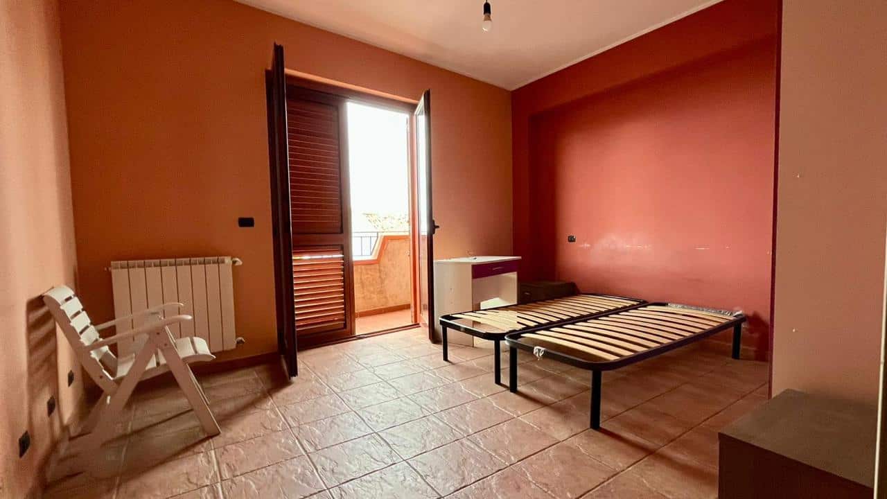Ripostiglio camera da letto vuota con letto a castello, balcone, calde pareti colorate e pavimento in piastrelle, ideale per affitti e investimenti immobiliari.