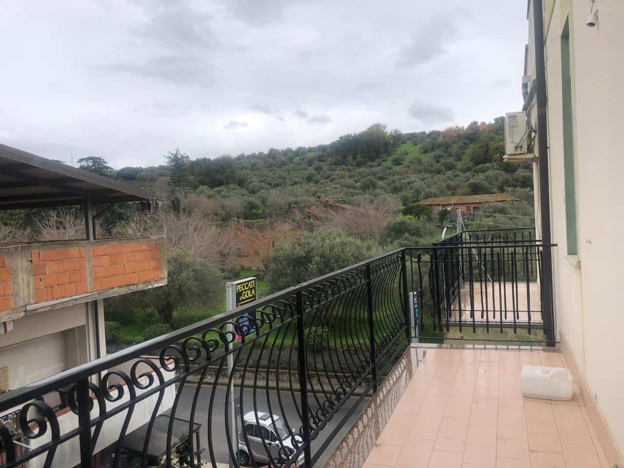 Ampio balcone con vista sulle colline e sul paesaggio verde circostante, perfetto per rilassarsi e godersi la natura, con pavimentazione in ceramica e ringhiera in ferro battuto.