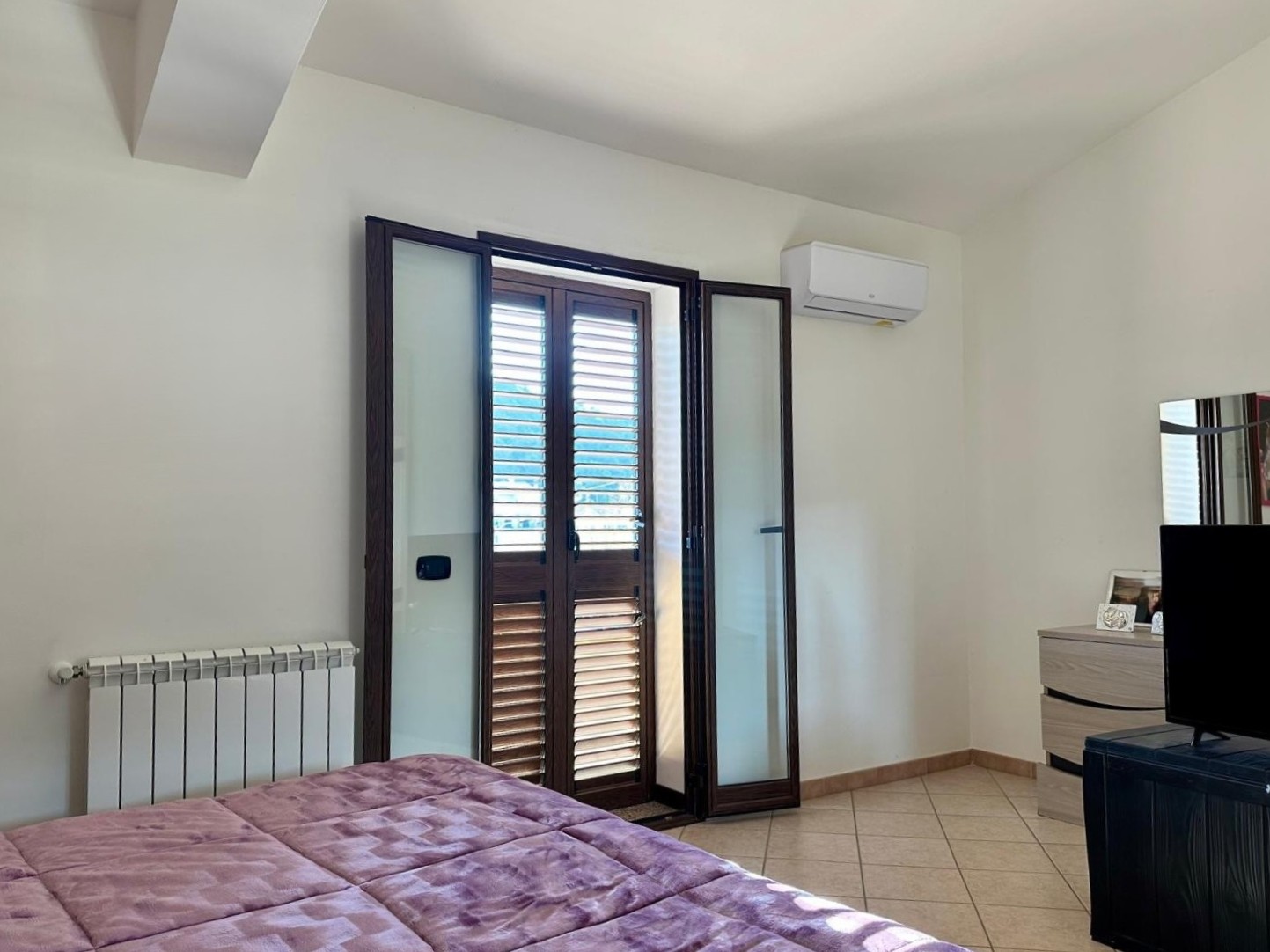 Ampio balcone con persiane in legno e aria condizionata, ideale per camere da letto luminose e moderne.
