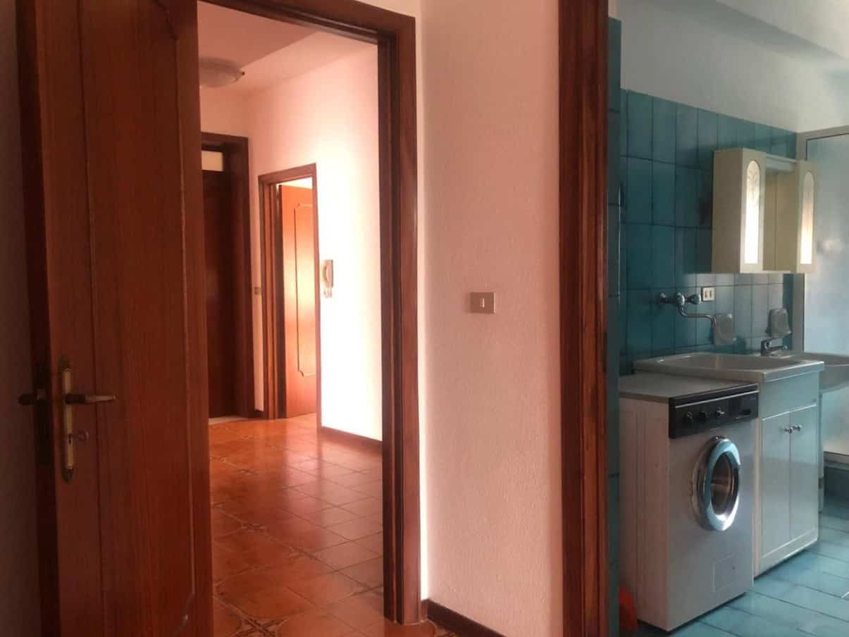 Lavatrice all'interno di appartamento con mobili cucina e pareti azzurre, vista di un corridoio in stile classico, perfetto per immobili in vendita o affitto.