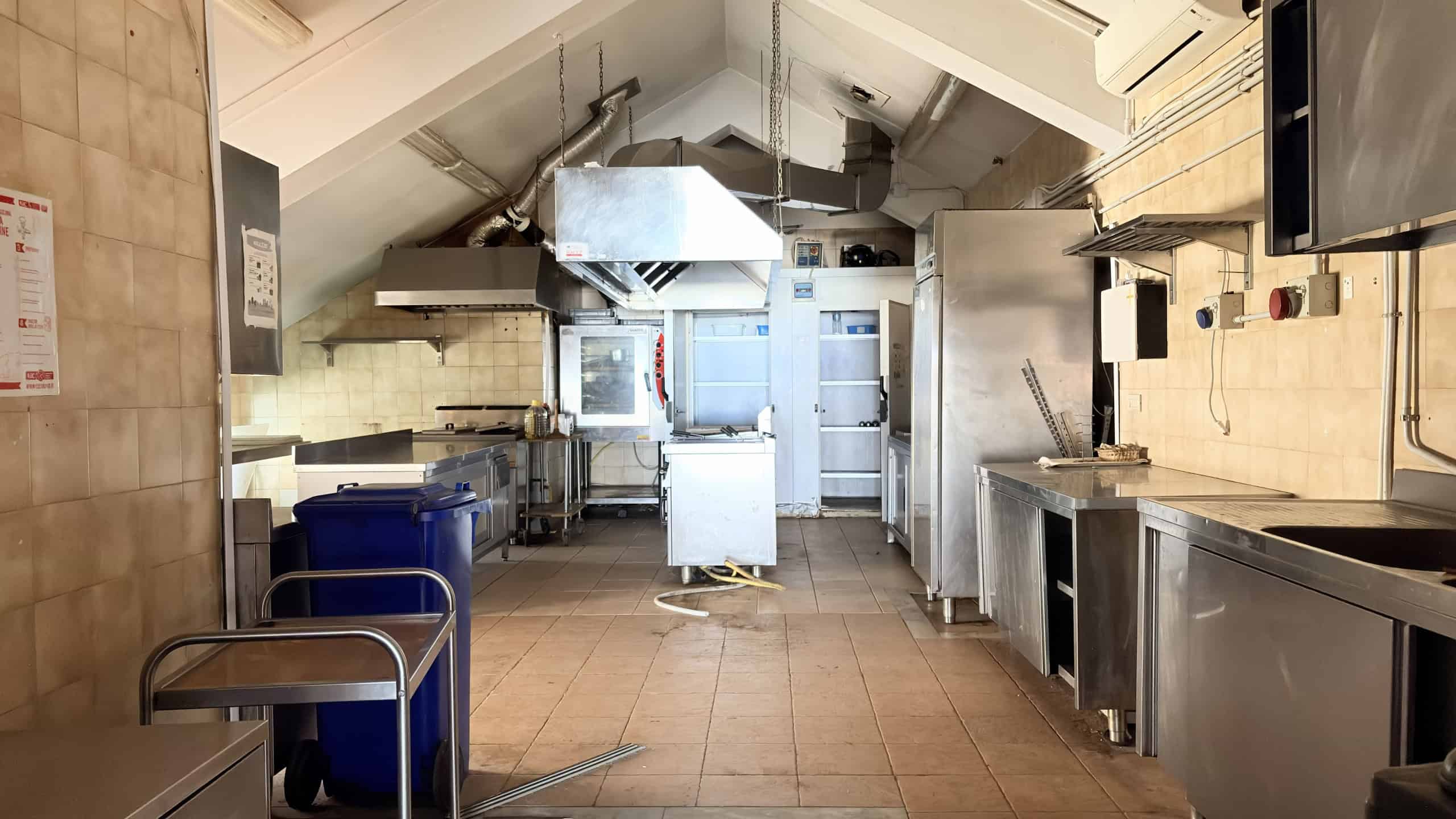 Lavagna cucina industriale in acciaio inox, ambiente professionale con attrezzature per ristorazione, cucina commerciale, stile industriale, cucina ristorante, locale gastronomico, attrezzature per cucine professionali.