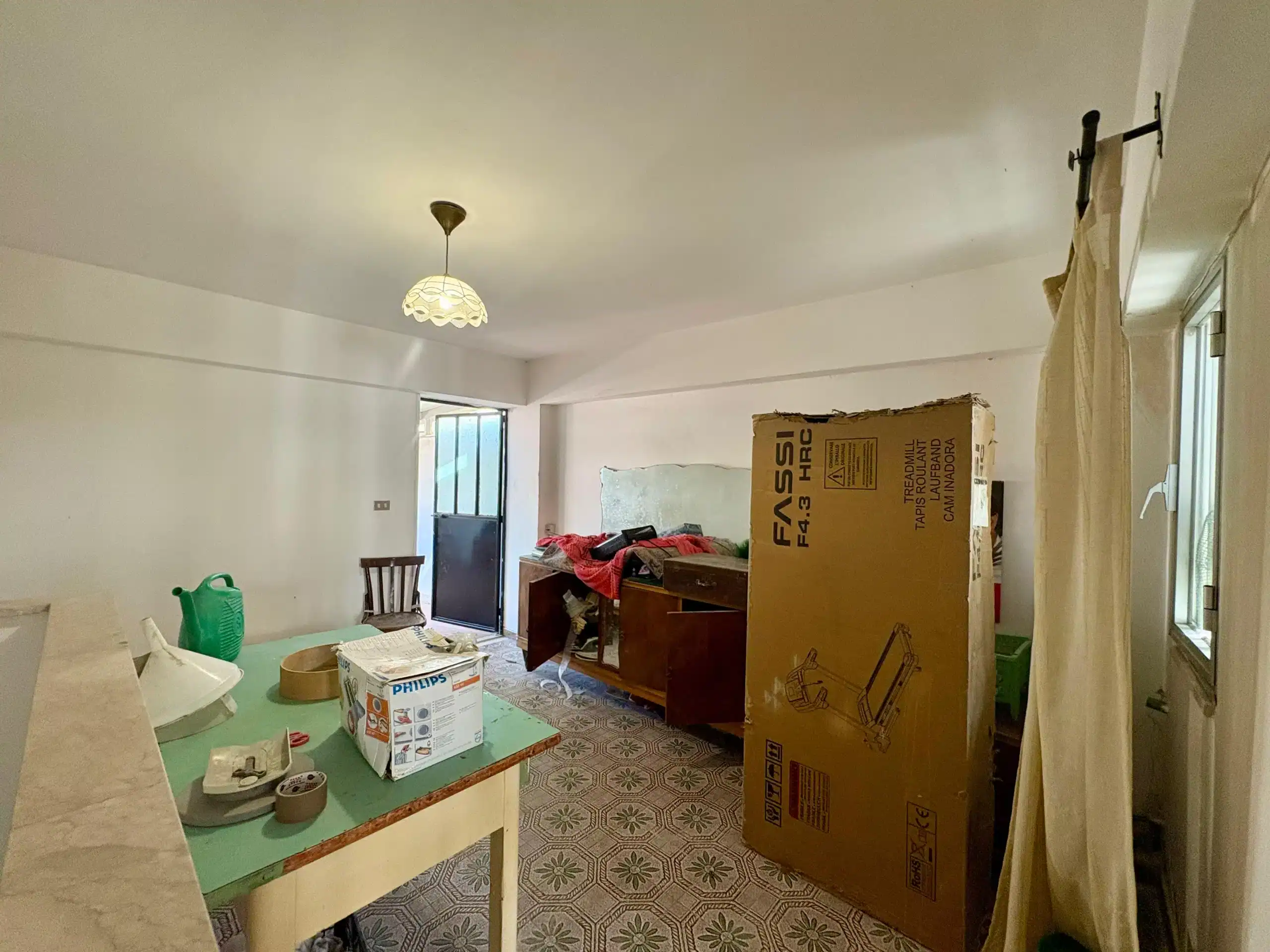 1. Immagine di un soggiorno in fase di ristrutturazione con scatole, materiali e mobili in attesa di sistemazione.