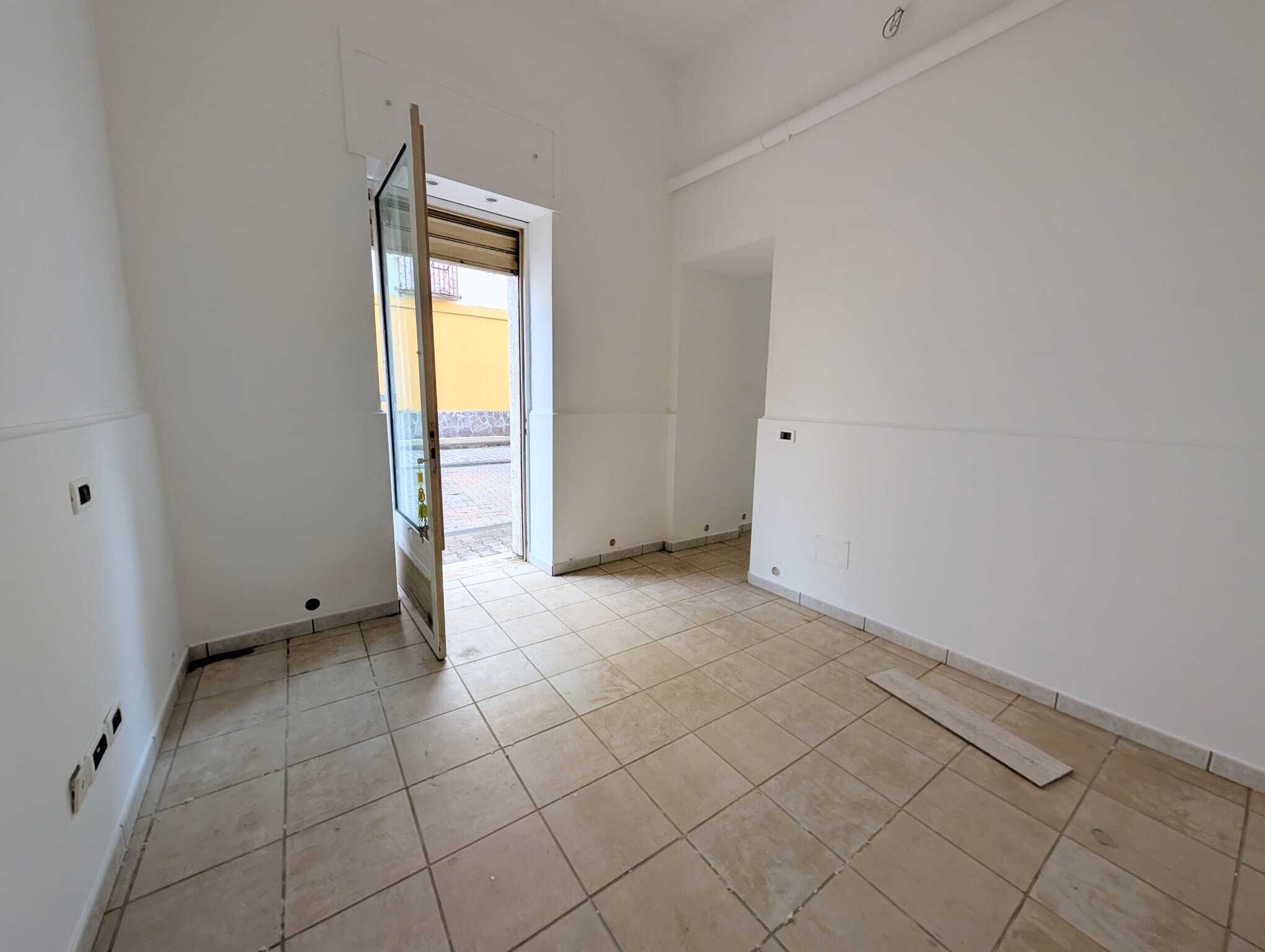 Elegante locale commerciale o ufficio in fase di ristrutturazione con ingresso luminoso e pavimento in piastrelle beige, pronto per personalizzazione e attività commerciali a NextCasa.