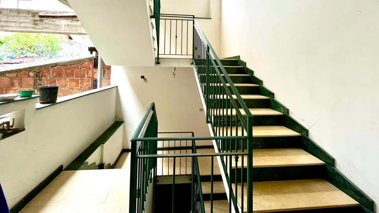 Trappa in stile moderno con ringhiera verde scuro, ideale per scala interna in appartamenti e case a NextCasa. Design funzionale e resistente per spazi abitativi eleganti e sicuri.