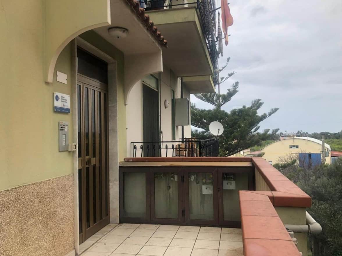 Balcone di appartamento con vista su alberi e edificio residenziale, dotato di veranda e spazio esterno con mobili da esterno e satellite, perfetto per vivere in quartiere tranquillo e attivo.