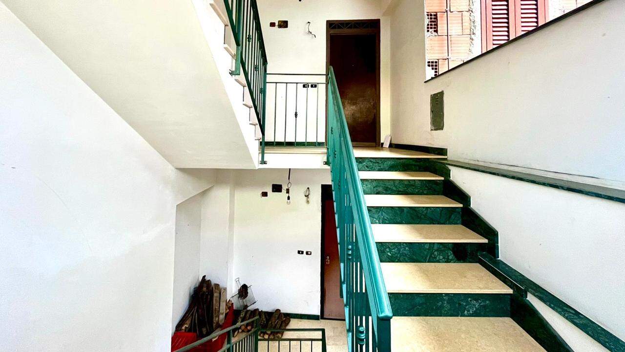 Scala interna in edificio residenziale con gradini in marmo verde e beige, balaustra in e poltrona di sicurezza. Ideale per appartamenti moderni e ristrutturazioni, ottima soluzione per spazi funzionali e sicuri.