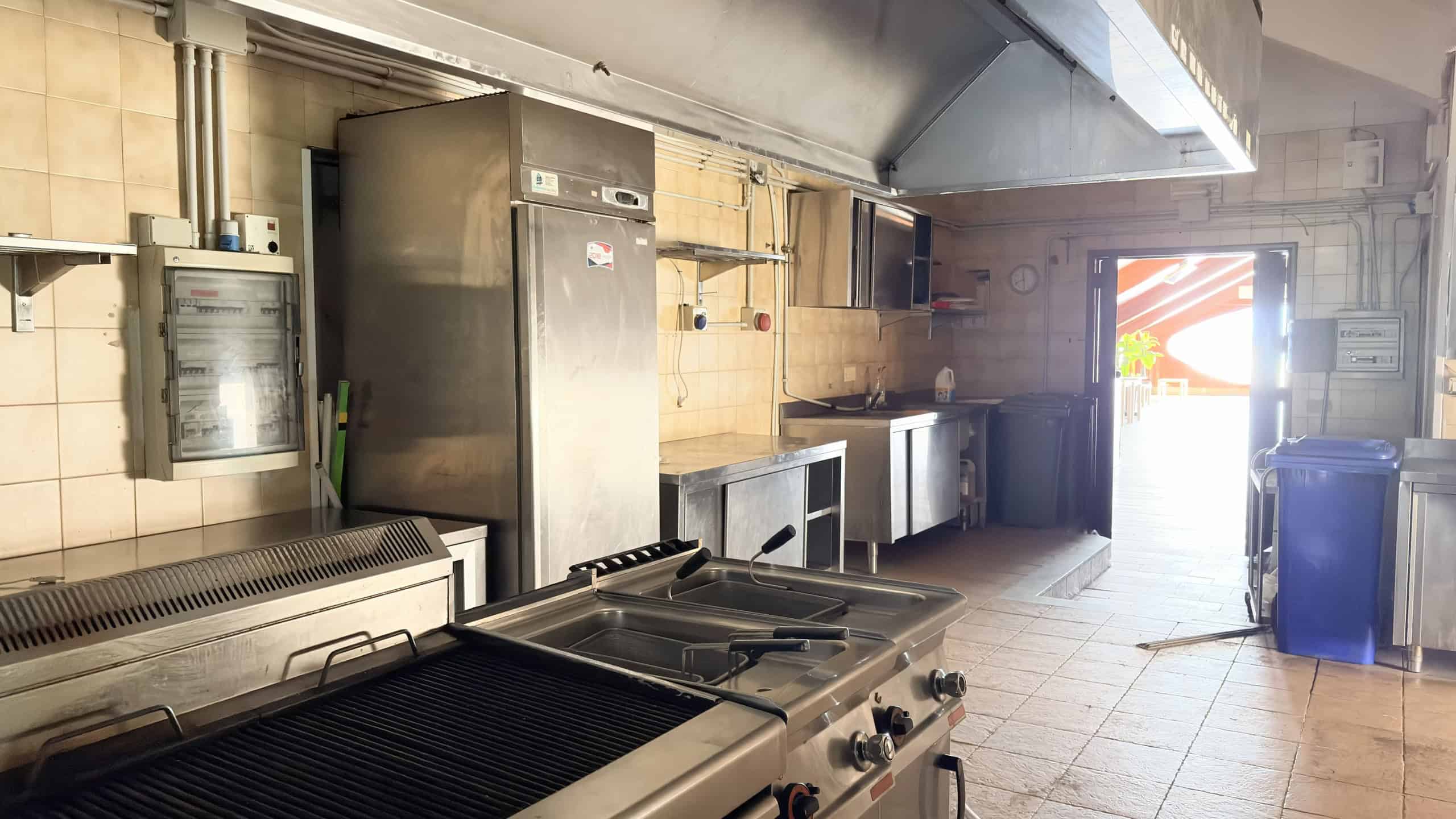 Cucina industriale in stile professionale con attrezzature in acciaio inox, piani di lavoro spaziosi e frigoriferi per ristoranti, ideale per attività di ristorazione e catering.
