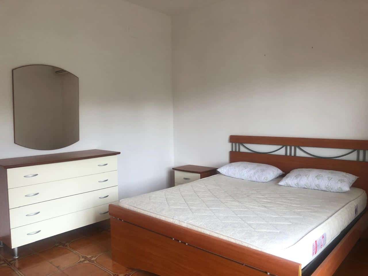 1. Cameretta matrimoniale con letto in legno, comodini e armadio in stile semplice, ideale per affitti turistici o residenziali.