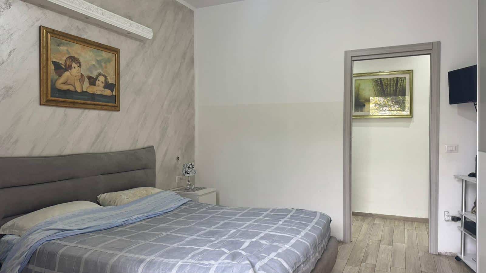 Letto matrimoniale in arredamento moderno con parete decorativa e opere d'arte, ambiente accogliente e spazioso, ideale per immagini di immobili di lusso e soluzioni residenziali di NextCasa.