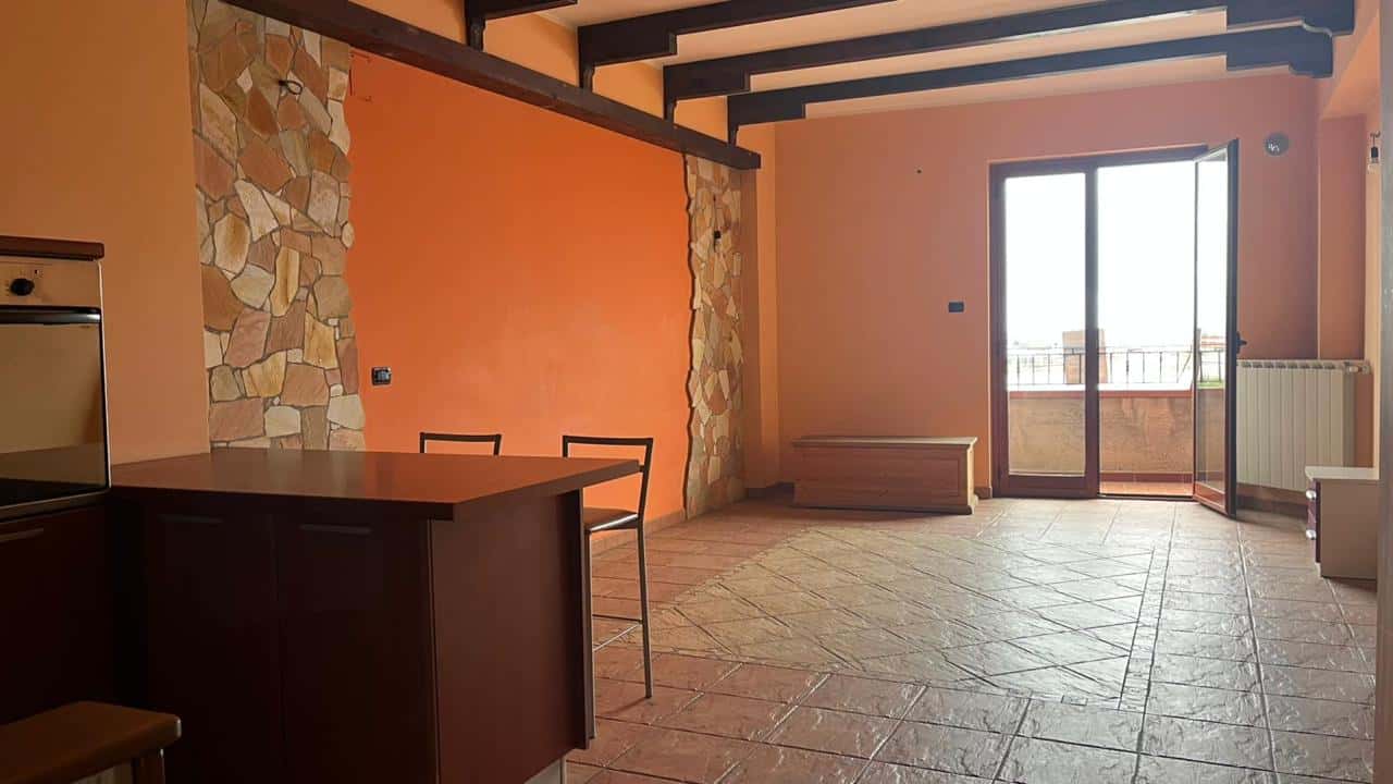 Ampio soggiorno con pareti arancioni, balcone, pavimento in gres porcellanato, spazio living luminoso, soluzione ideale per appartamenti in vendita o affitto a NextCasa.
