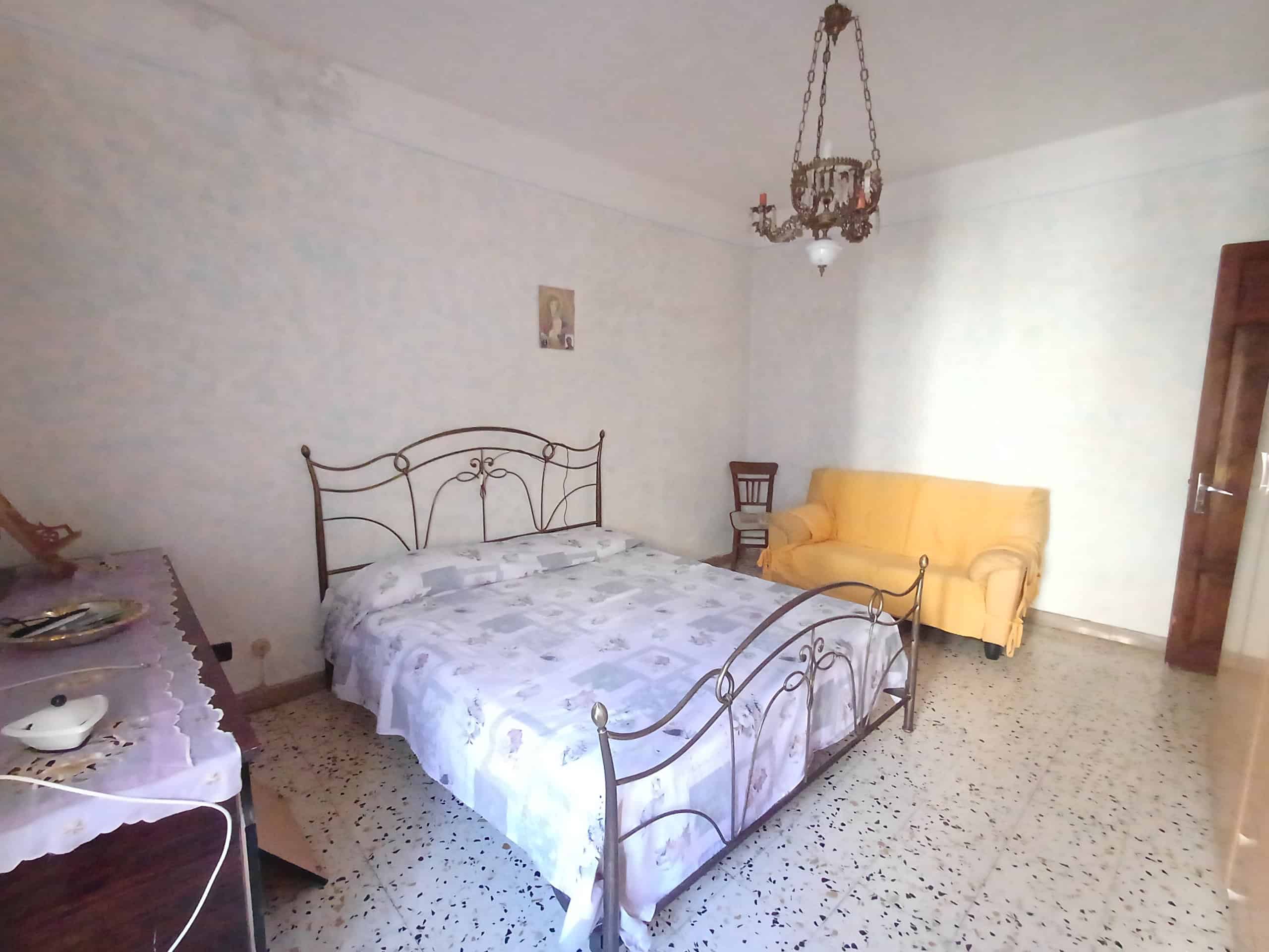 1. camera da letto con letto in ferro battuto, armadio e divano giallo in stile classico, arredamento semplice e funzionale.