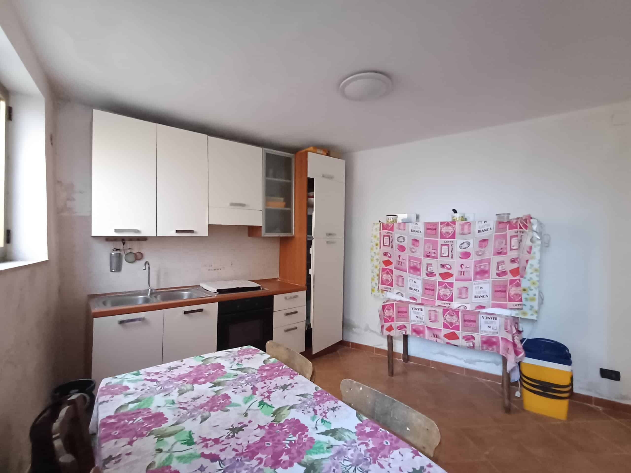 1. Cucina con mobili bianchi, angolo cottura con forno e lavabo, ambiente semplice e funzionale per la casa.