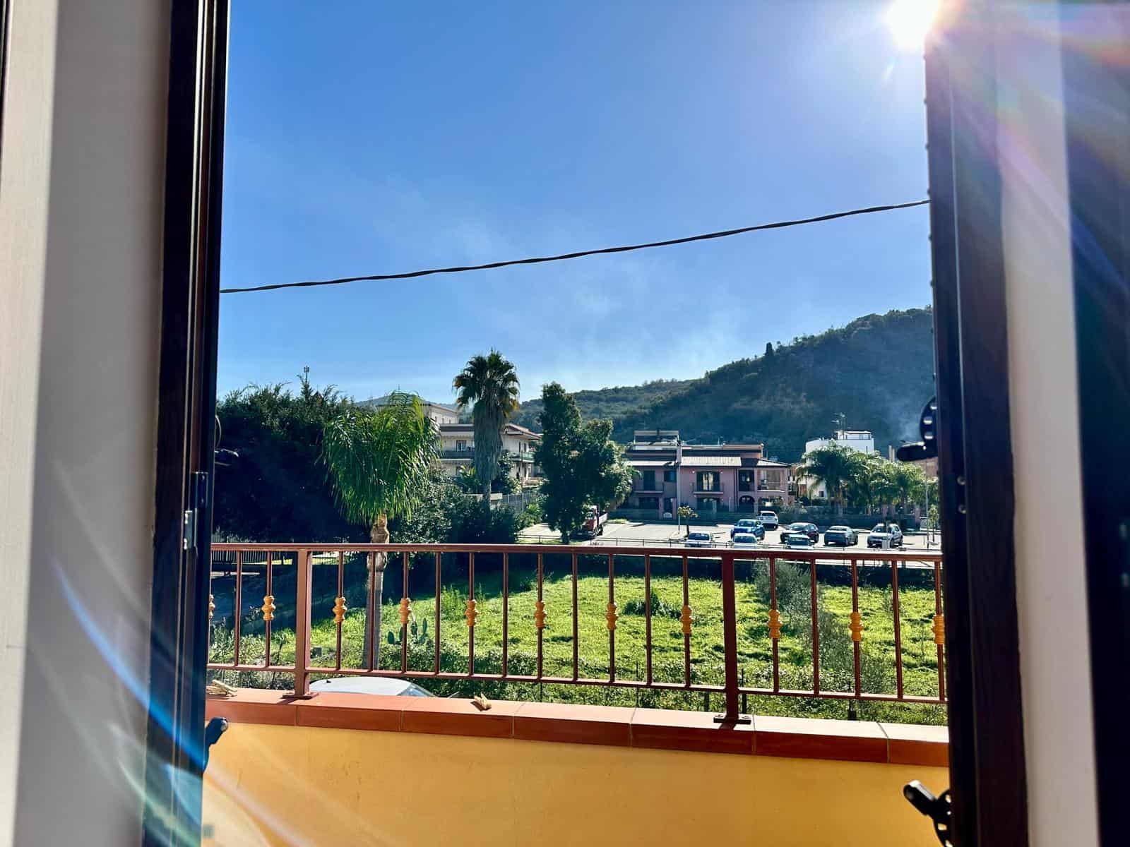 Vista mare dal balcone di un appartamento a NextCasa con cielo sereno e colline sullo sfondo, luminose e suggestive, perfetta per investimenti immobiliari e case al mare in vendita.