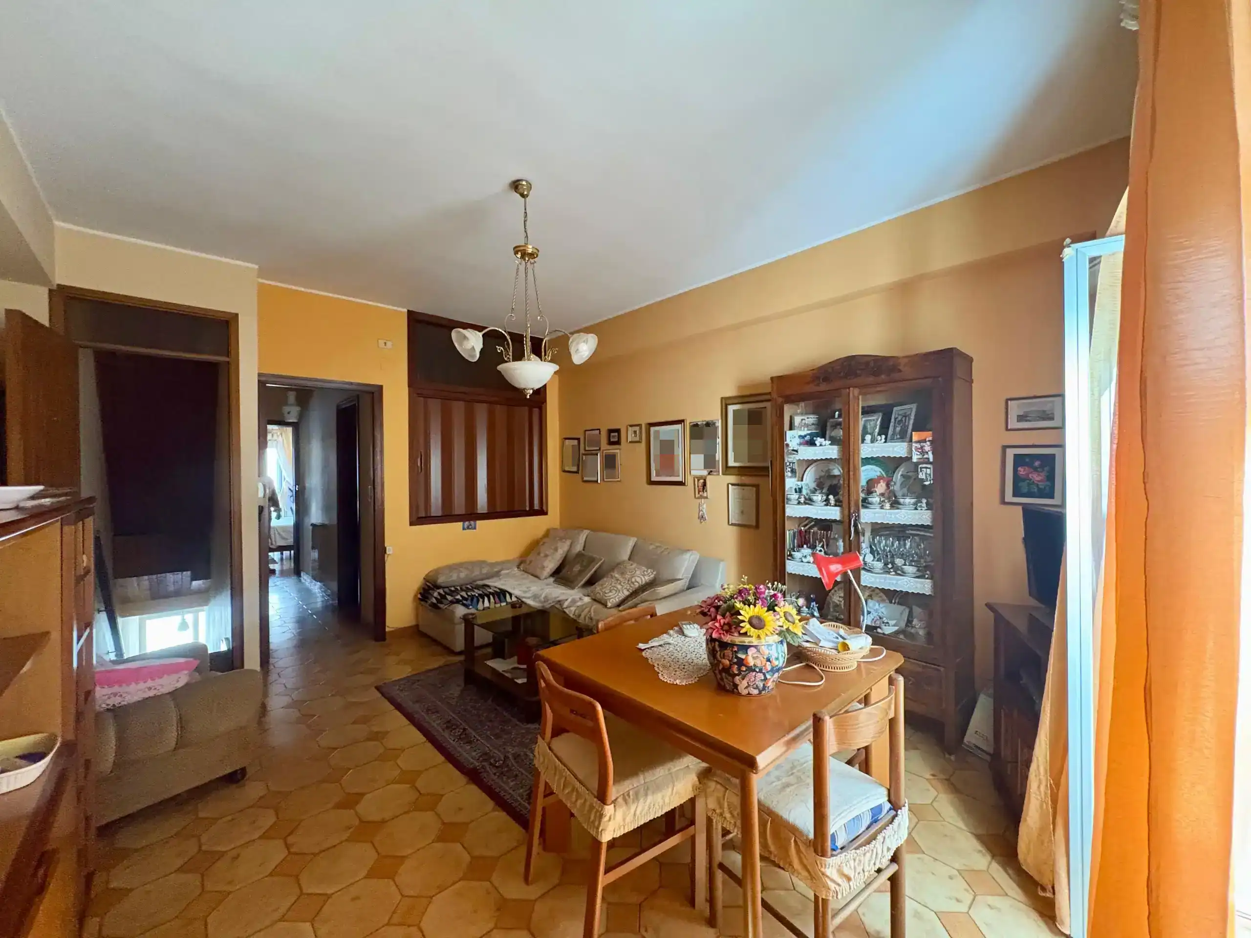 Appartamento in vendita con soggiorno spazioso, arredi classici, lampadario vintage e pareti gialle, ideale per acquisto casa con stile tradizionale.