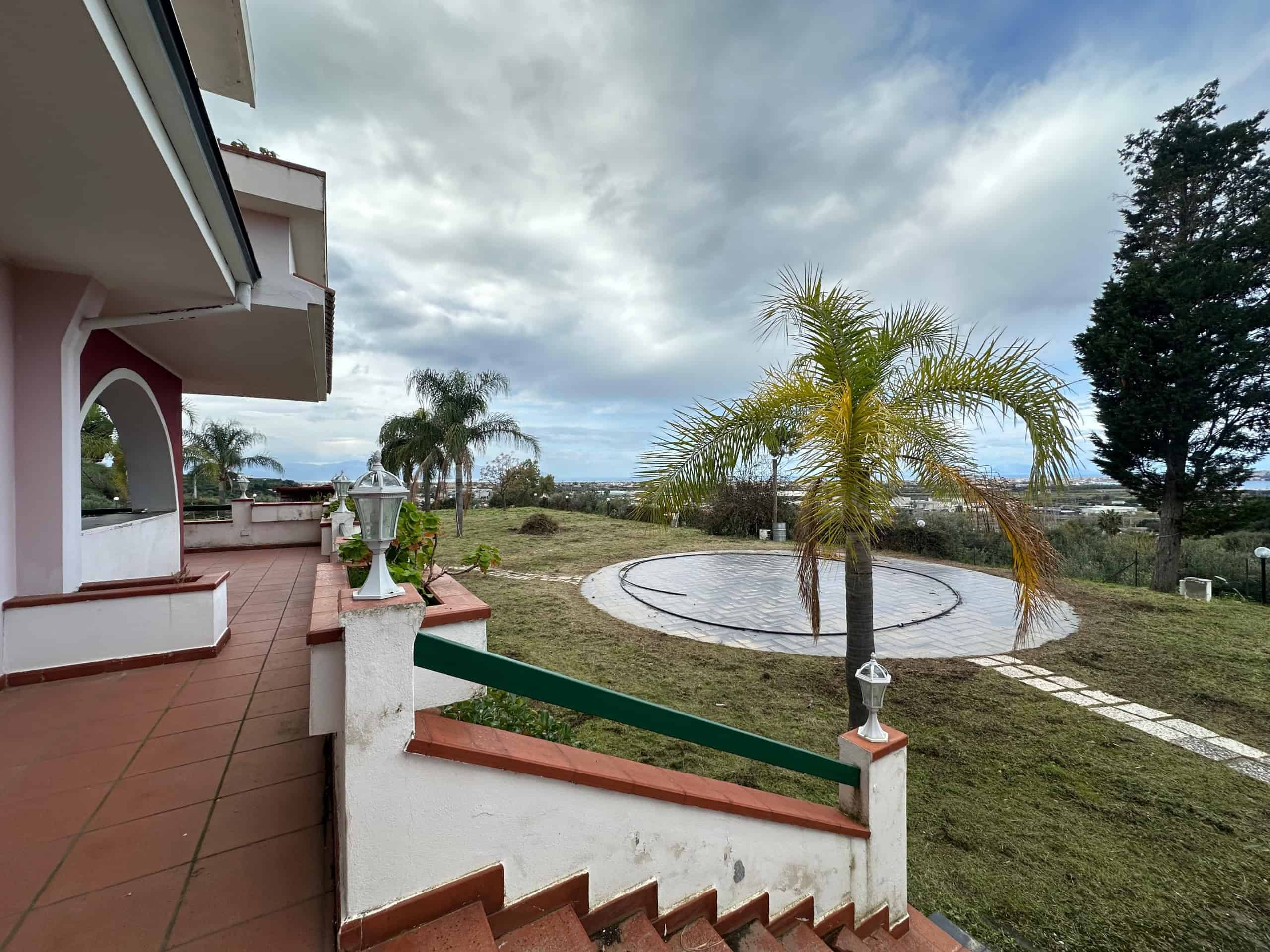 Ampio terrazzo con vista panoramica su giardino con palme, ideale per relax e convivialità, zona esterna ben curata, atmosfera tranquilla e immersa nel verde, preferibile per case e ville di prestigio.