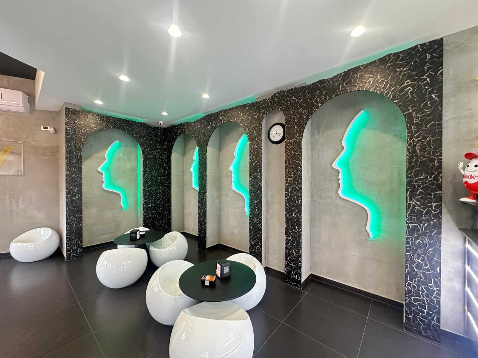 1. Murales di profili femminili futuristici con illuminazione a LED verdi, pareti in cemento con dettagli di pavimentazione nera, atmosfera moderna e accogliente.