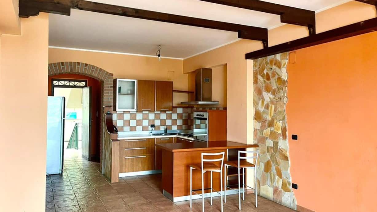 Arredamento cucina moderna in stile rustico con parete in pietra naturale e mobili in legno, ambiente caldo e accogliente, ideale per case di charme e ristrutturazioni innovative.