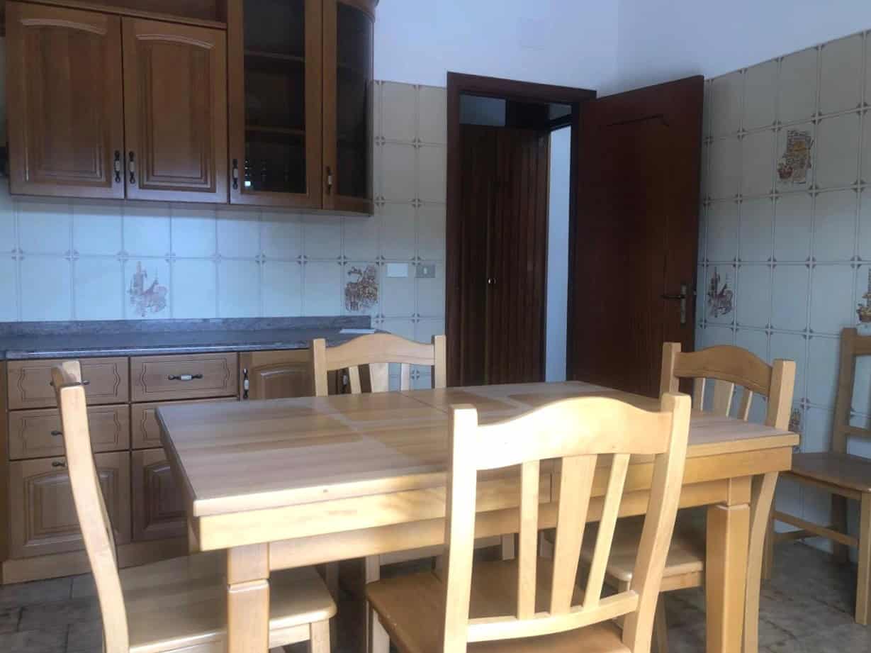 1. Cucina rustica con armadi in legno, tavolo da pranzo e pareti rivestite in ceramica decorativa, atmosfera accogliente e tradizionale.
