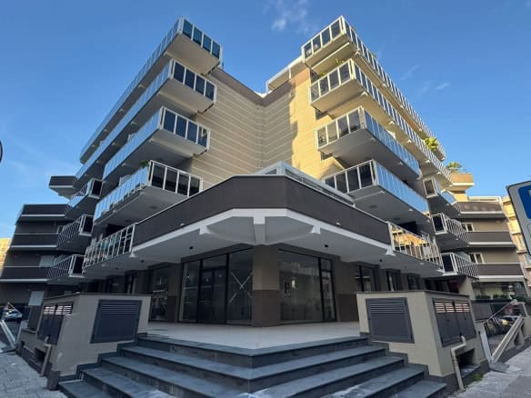 Moderno edificio residenziale con balconi in vetro, facciata elegante a più piani, appartamenti di design a NextCasa, soluzione abitativa di prestigio.