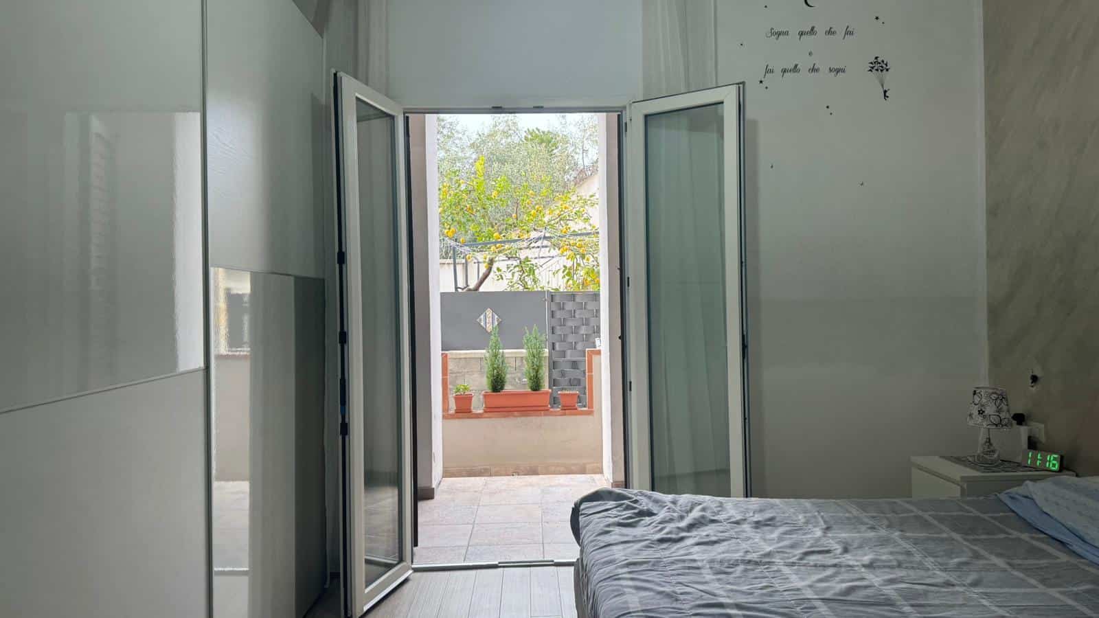 Balcone di casa moderna con porta a vetri e piante in vaso, vista su giardino, stile contemporaneo, luce naturale, interior design elegante e accogliente, ideale per appartamenti e case al mare.