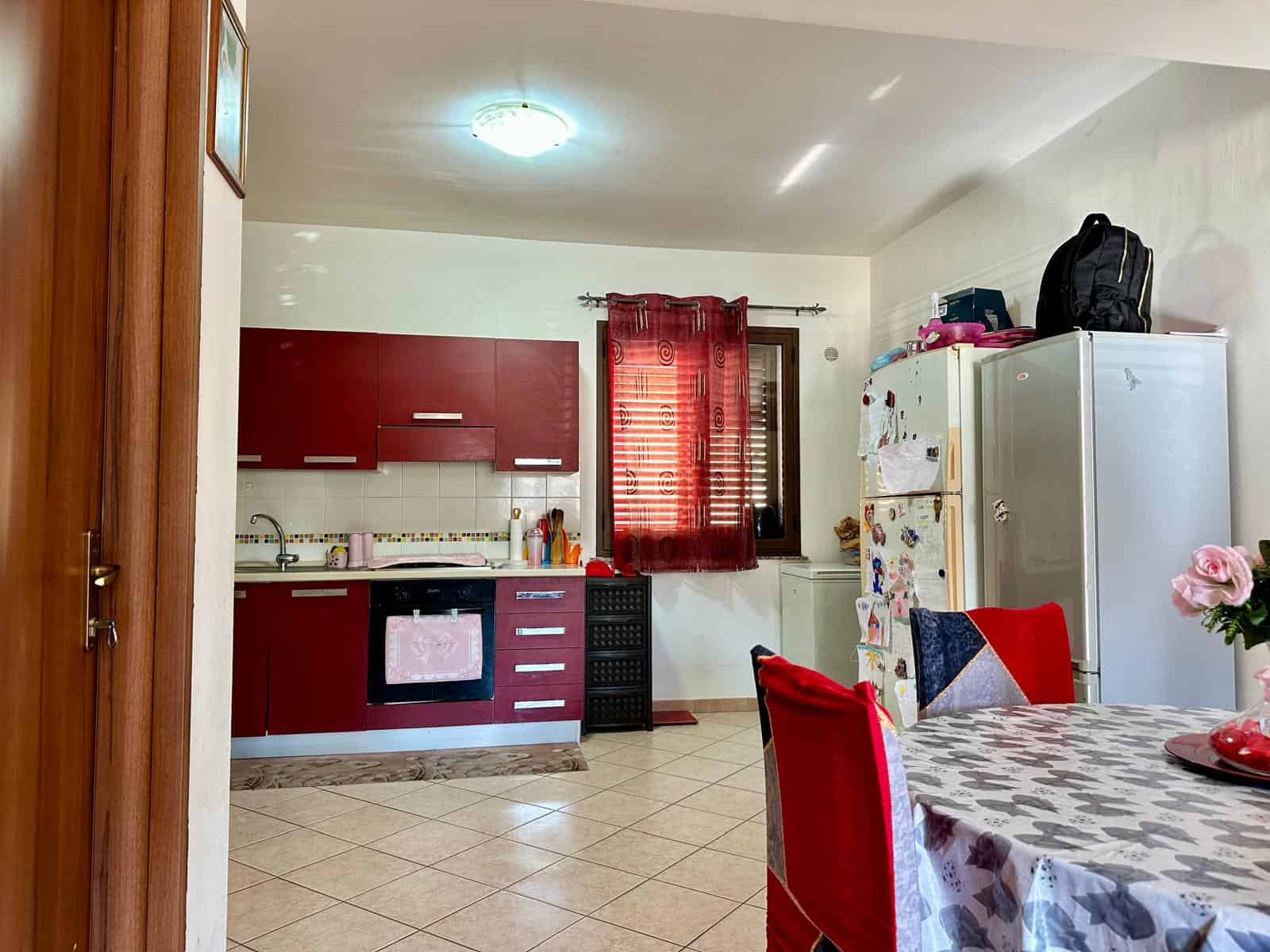 Armadio frigorifero cucina in stile classico con decorazioni e mobiletto alto, ambiente di casa con tavolo e sedie trapuntate, ideale per appartamento o villa in vendita o affitto.