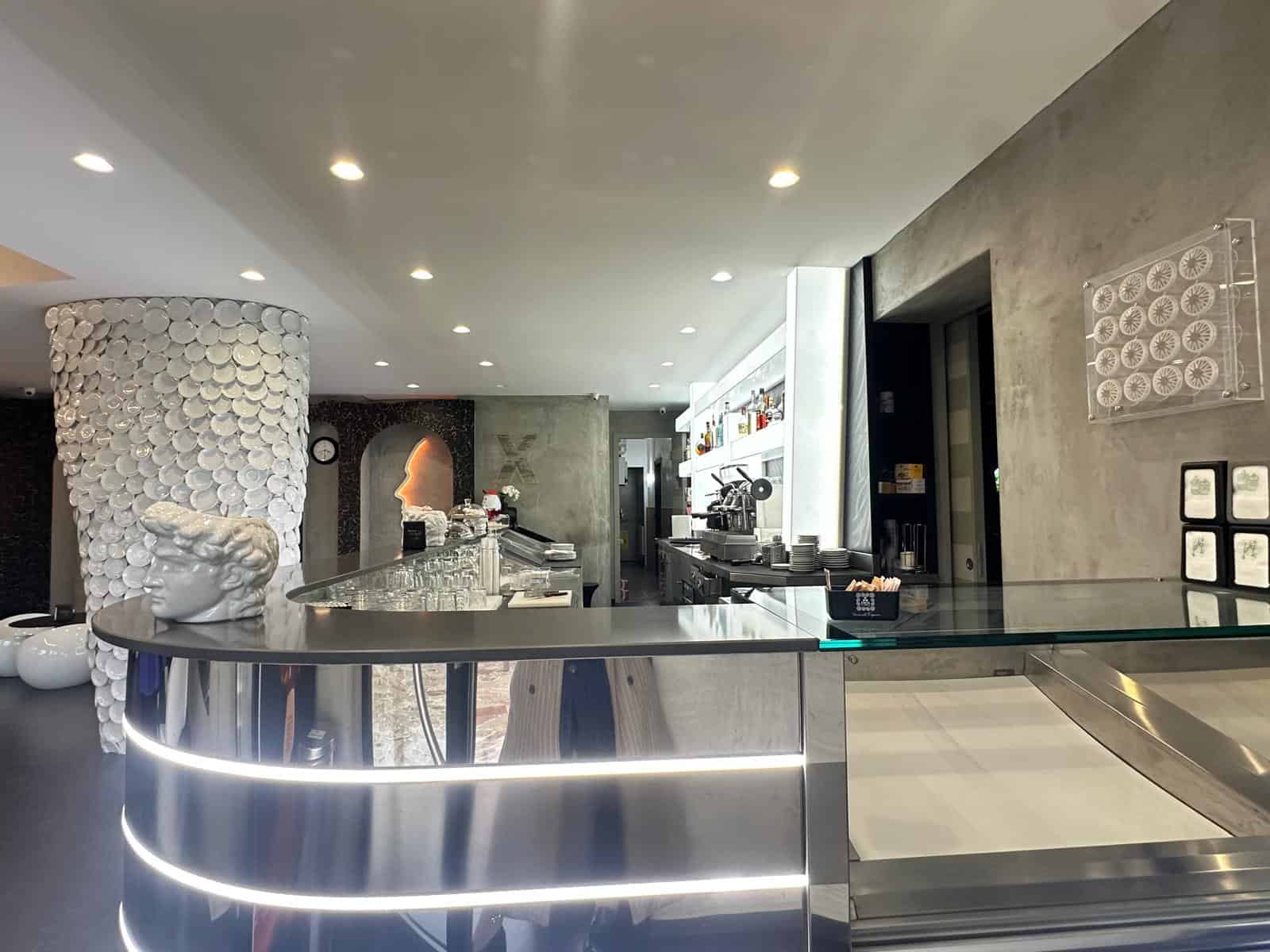 1. Banco bar moderno in acciaio con illuminazione a LED, arredamento elegante e dettagli di design nel ristorante NextCasa, locale di tendenza a Milano.