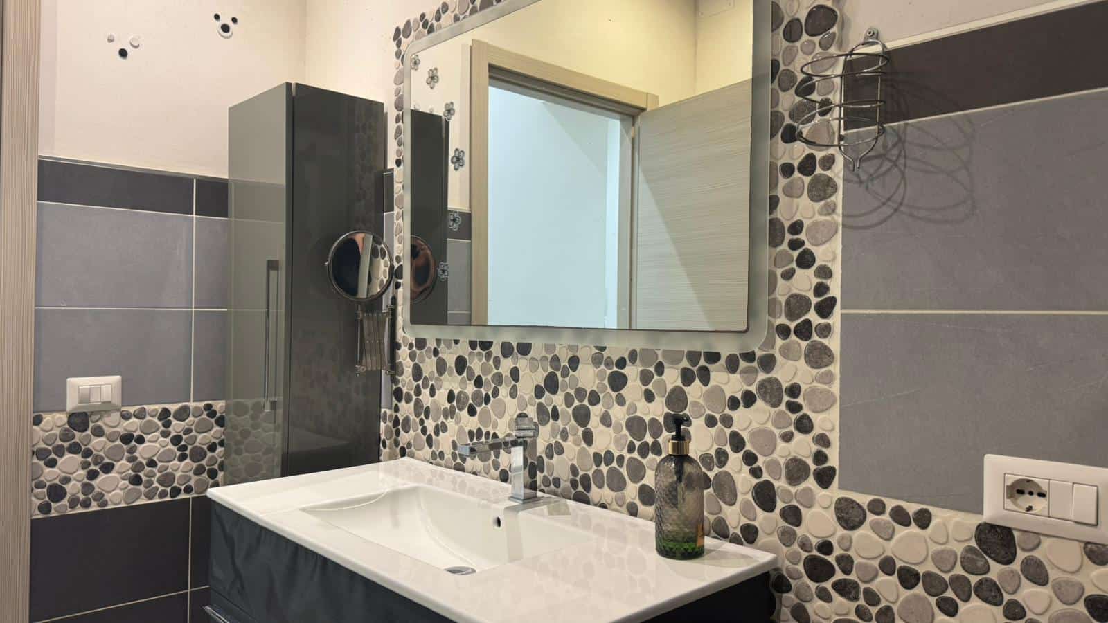Specchio e lavabo moderni in bagno, decorazioni con pietre naturali grigie e accessori eleganti, ambiente funzionale e di design, ideale per appartamento in affitto o ristrutturato alla perfezione.