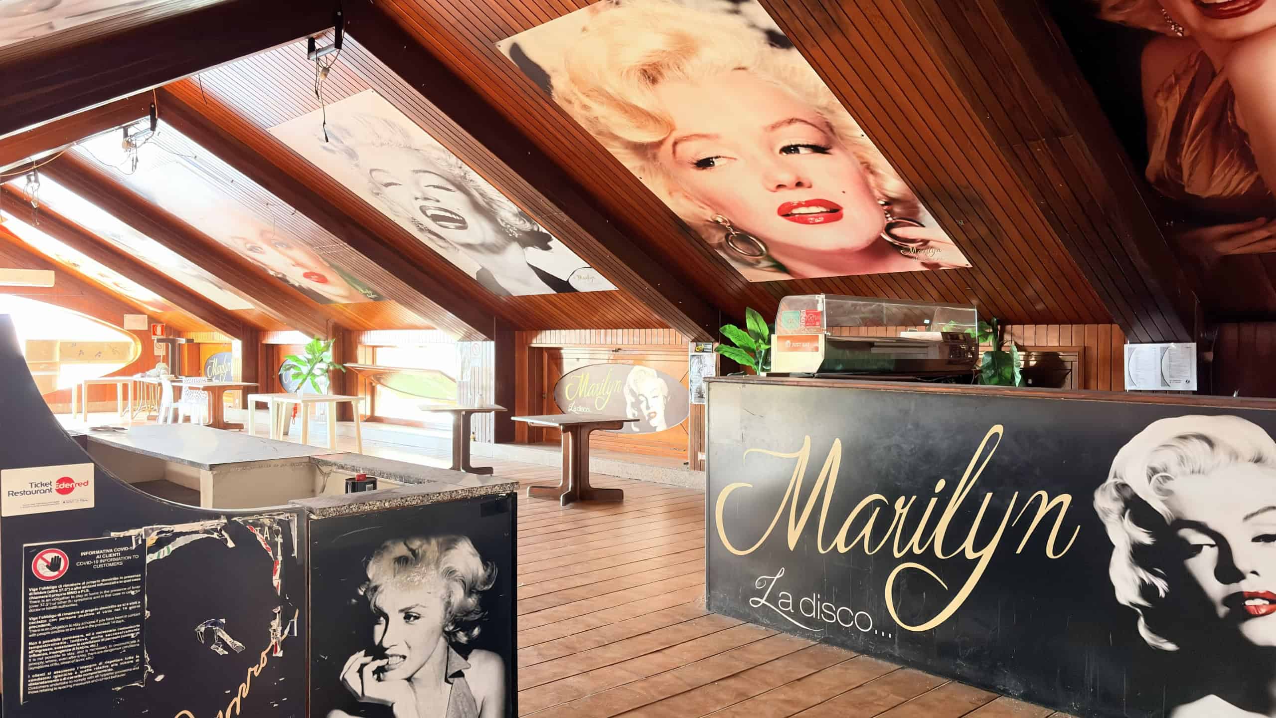 Interieur elegante di un bar con decorazioni di Marilyn Monroe e fotografie iconiche, ambientazione accogliente con soffitto in legno e luci soffuse, ideale per eventi e ritrovi.