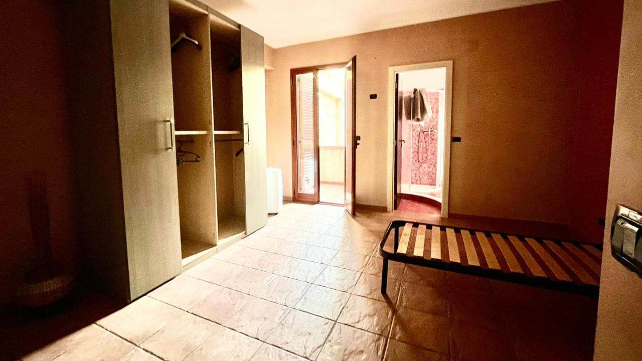 Armadio a due ante e letto in una stanza con porta finestra e bagno.