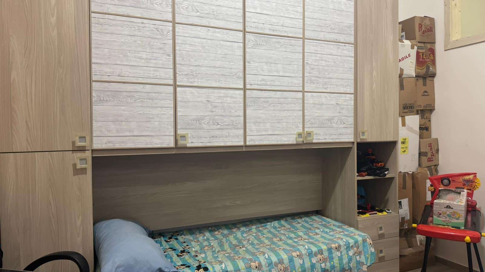Armadio a muro in legno chiaro con cassetti e ante battenti, spazio di stoccaggio e confortevole zona letto, ideale per arredare camere da letto funzionali e moderne.