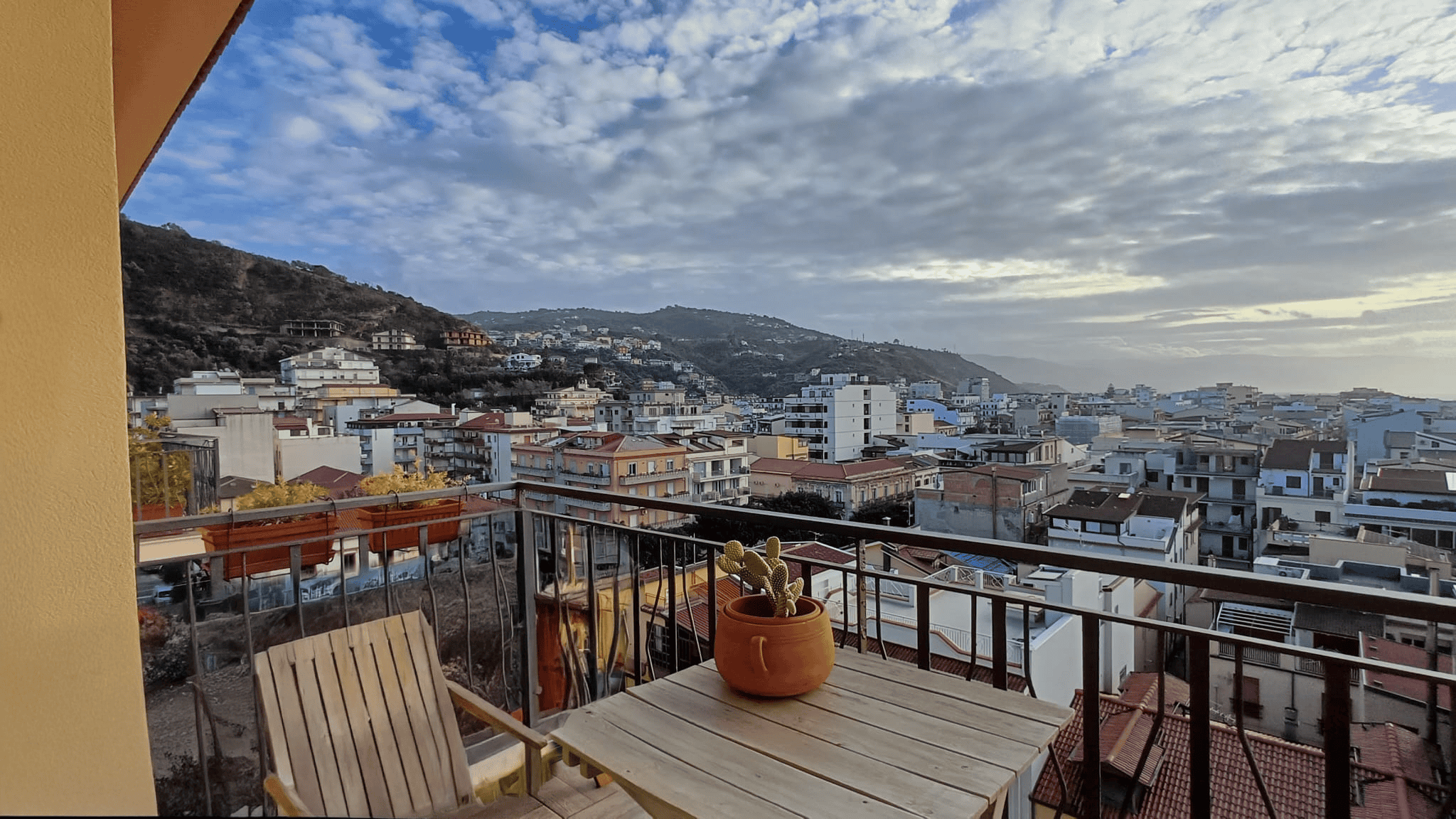 Vista panoramica sulla città e sulle colline dall'ampio balcone di un appartamento a NextCasa, ideale per vivere in modo confortevole e immerso nella natura.