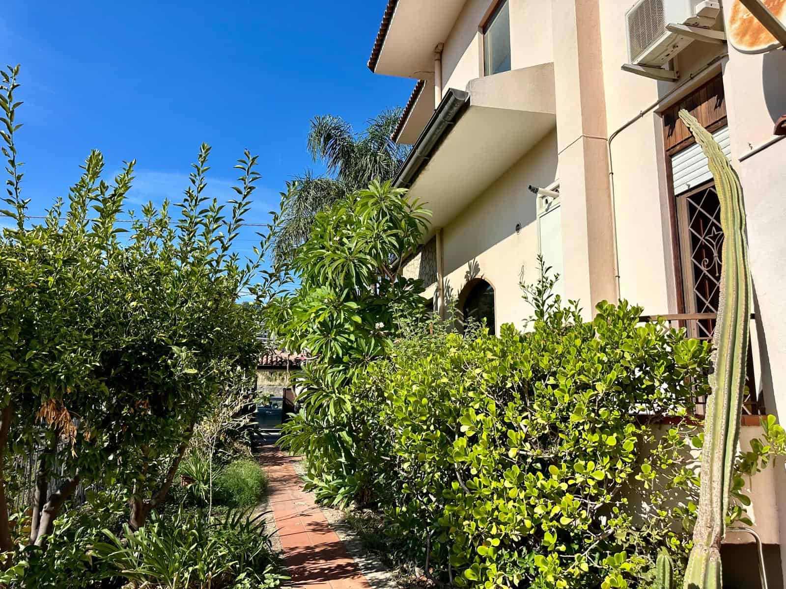 Veranda tranquilla con giardino rigoglioso e piante tropicali, ideale per rilassarsi e godersi il sole in un ambiente accogliente e privato a due passi dal centro.