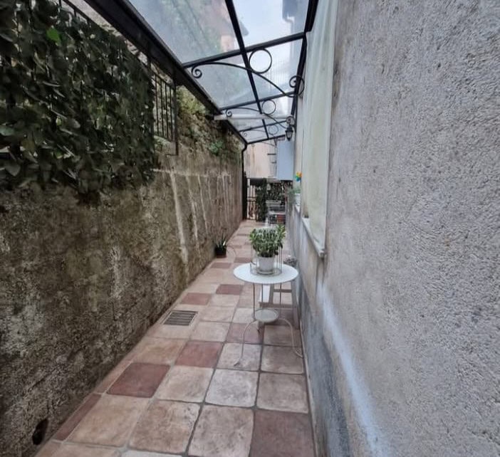 1. Contrada esterna di un appartamento con vasi di piante e veranda in vetro, in stile rustico e funzionale.