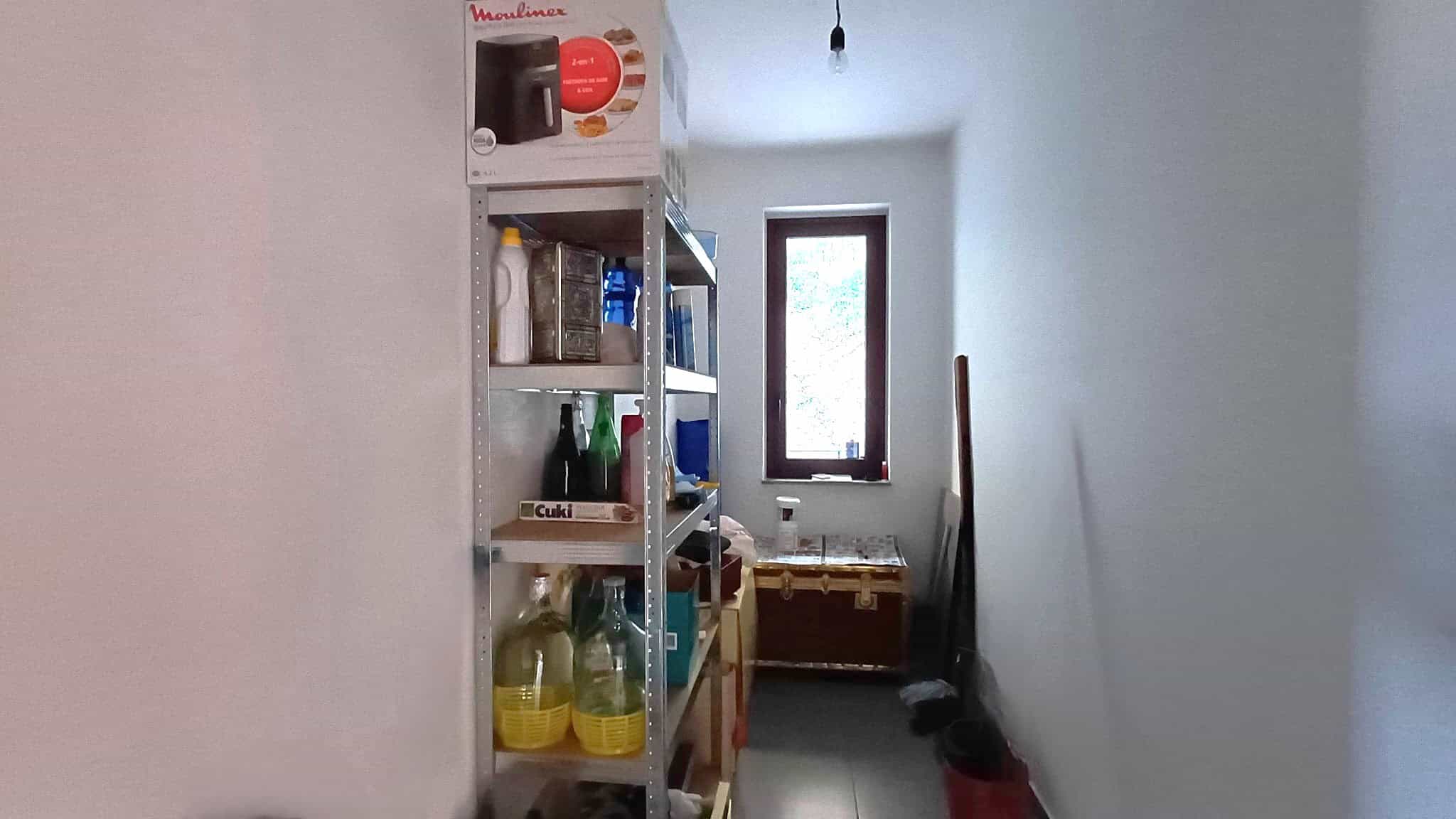 1. Estanteria in metallo con scatole e bottiglie, spazio di archiviazione per cucina o magazzino, ambiente luminoso con finestra.