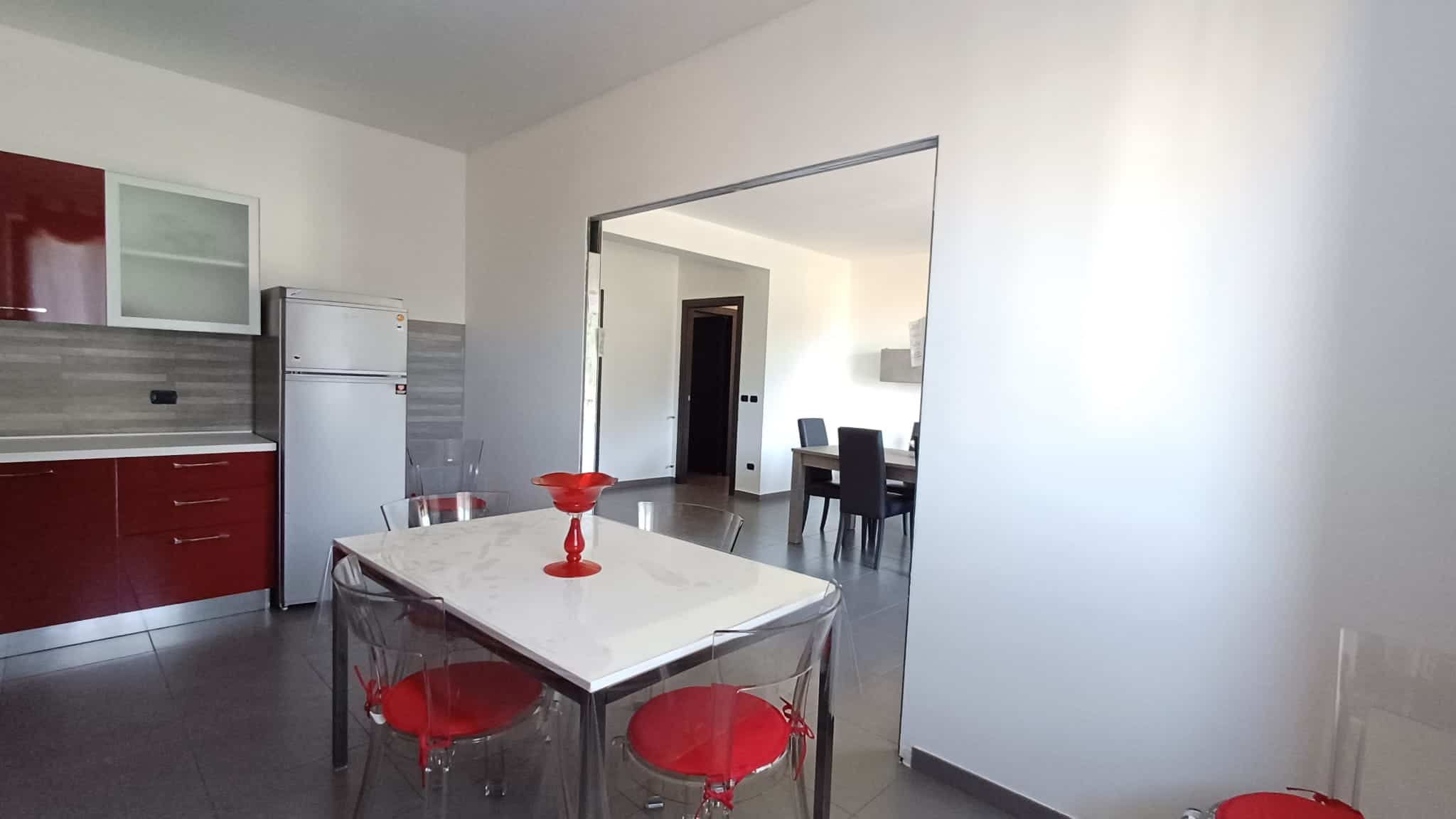 1. Cucina moderna con mobili rosso e accessori trasparenti in casa NextCasa, design funzionale e stile contemporaneo.