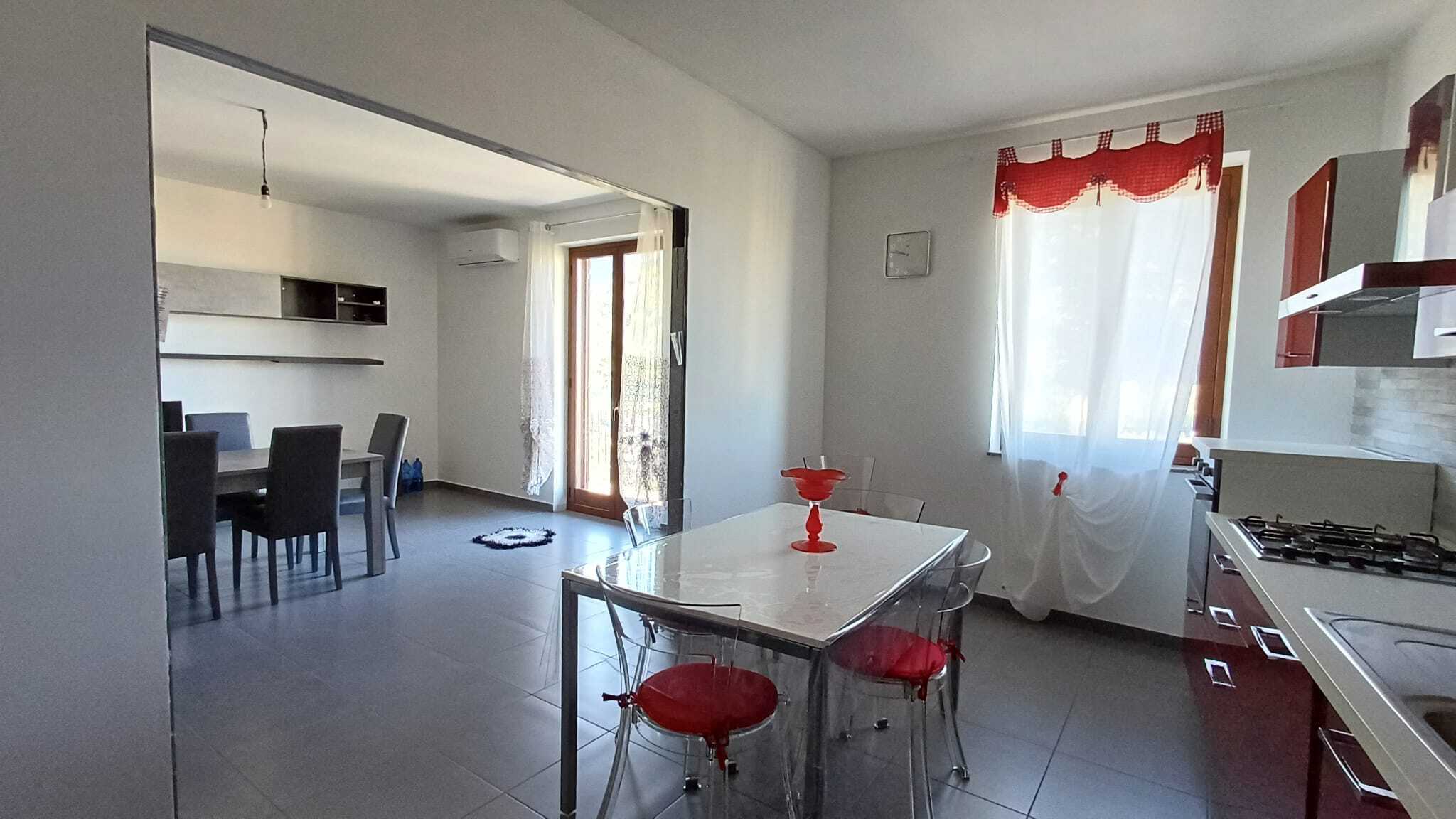 Vista cucina e zona pranzo moderna e luminosa, con finestre che lasciano entrare molta luce naturale, mobili eleganti e dettagli colorati, ideali per vivere con comfort e stile.
