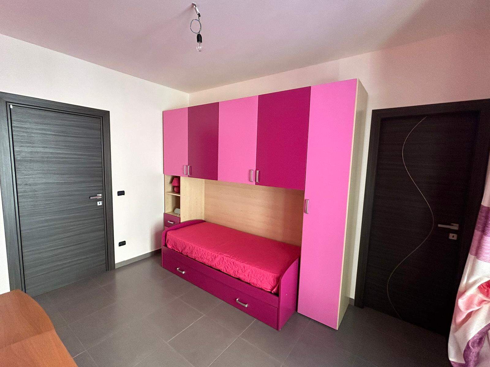 Letti a castello color rosa con armadio integrato, spazio ottimizzato per camerette bambini, mobili moderni e funzionali, ideale per ambienti giovani e vivaci, soluzioni salvaspazio per casaNextCasa.