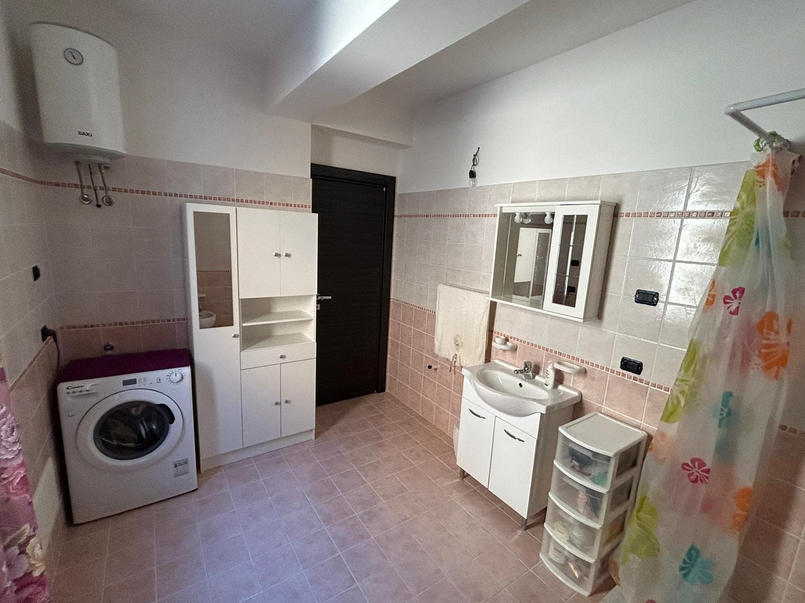 Lavanderia con lavatrice, armadietti e specchio, stanza funzionale e luminosa, perfetta per servizi domestici e stoccaggio, in un appartamento moderno e ben tenuto.