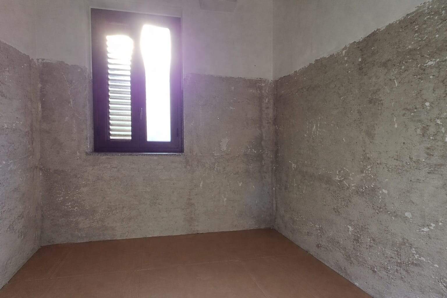 Parete in prospettiva con finestra in muratura grezza, ristrutturazione casa, processi di edilizia, rinnovamento interni, materiali edili, trasformazione abitativa, costruzione moderna.