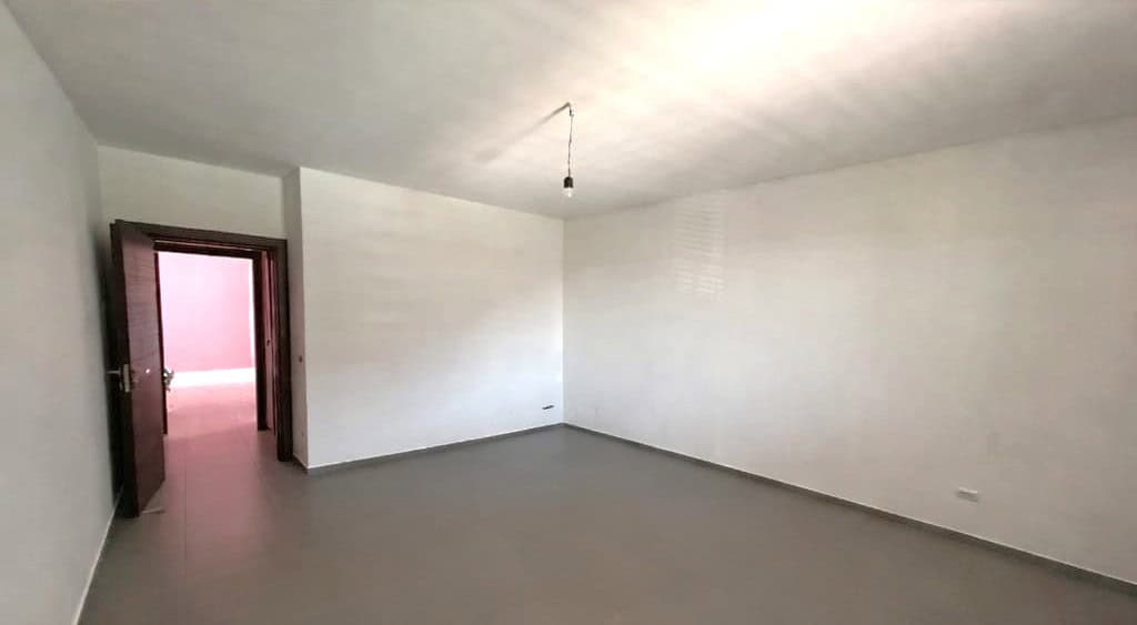 Spazio vuoto in appartamento di nuova costruzione con pareti bianche e pavimento in piastrelle grigie, pronto per arredare.