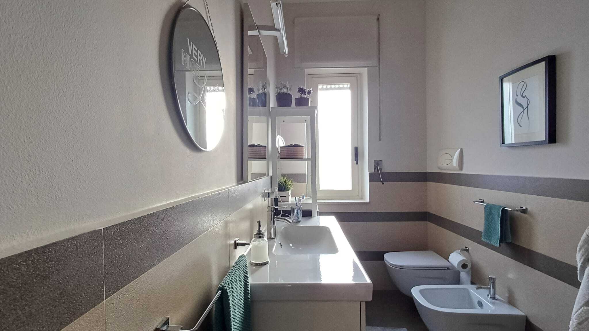 1. Bagno moderno con lavabo, bidet e toilette, arredato con dettagli di design e piante decorative, in un ambiente luminoso e confortevole.