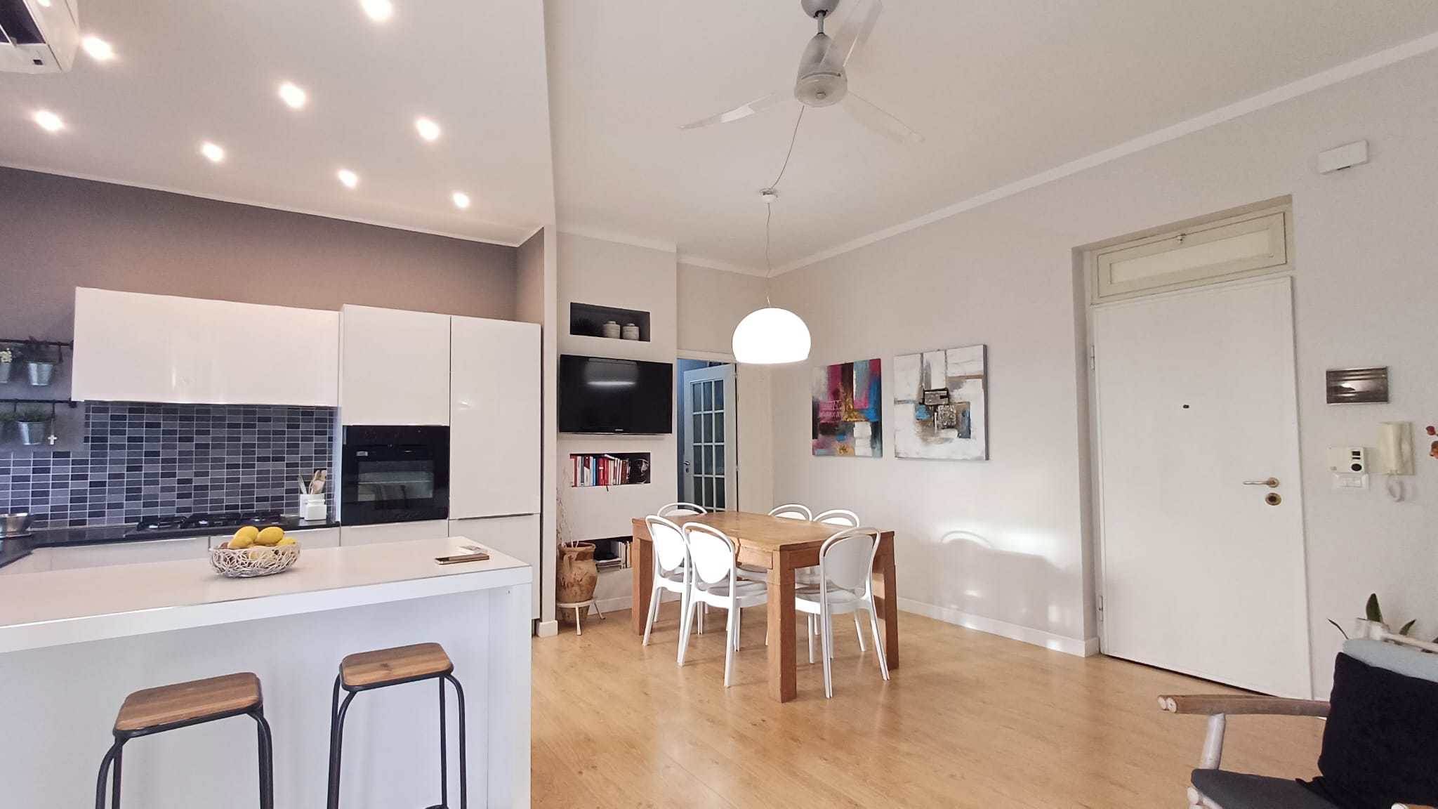 Lavastoviglie e forno integrati in cucina moderna con tavolo da pranzo e pareti decorate, ambiente luminoso e accogliente ideale per abitazioni di qualità.