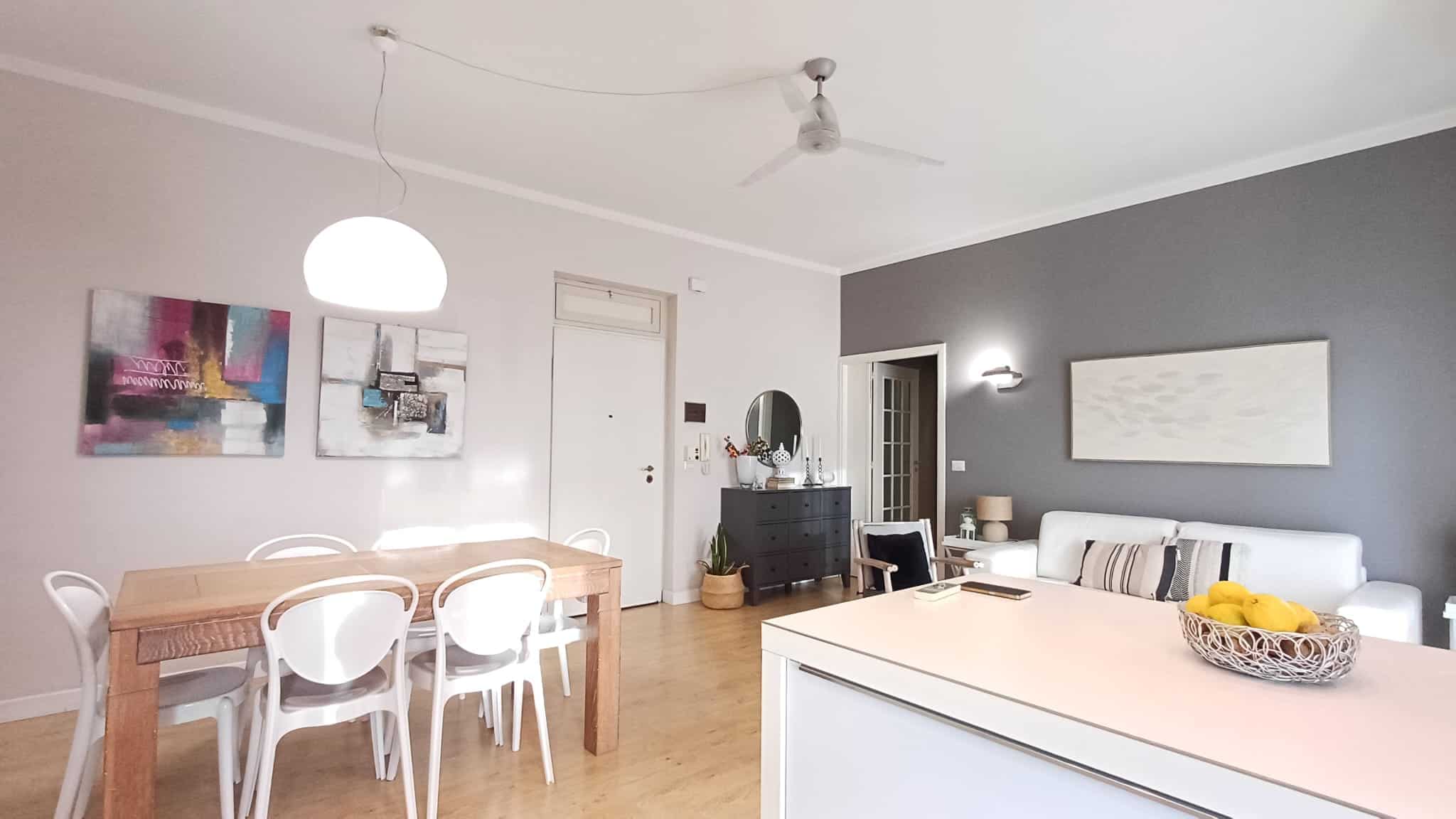 Ampio soggiorno con zona pranzo, arredi moderni, pareti colorate e decorazioni artistiche, ideale per vivere confortevolmente in appartamento di design.